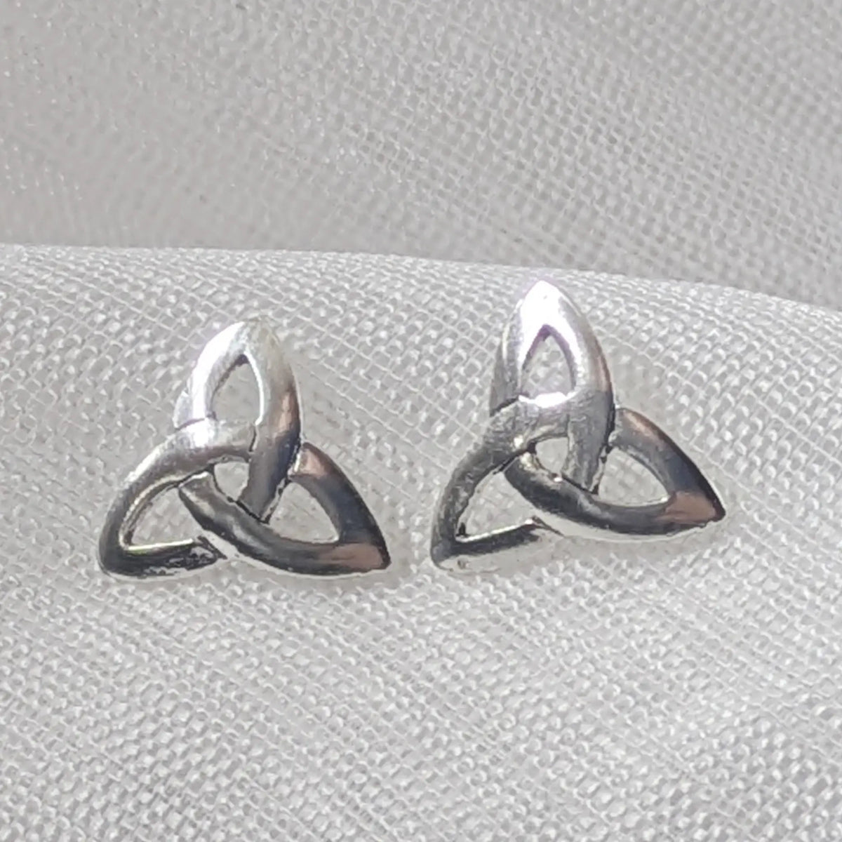 Nahaufnahme von zwei glänzenden 925 Silber Ohrsteckern im durchbrochenen Triquetra-Design (keltischer Knoten).