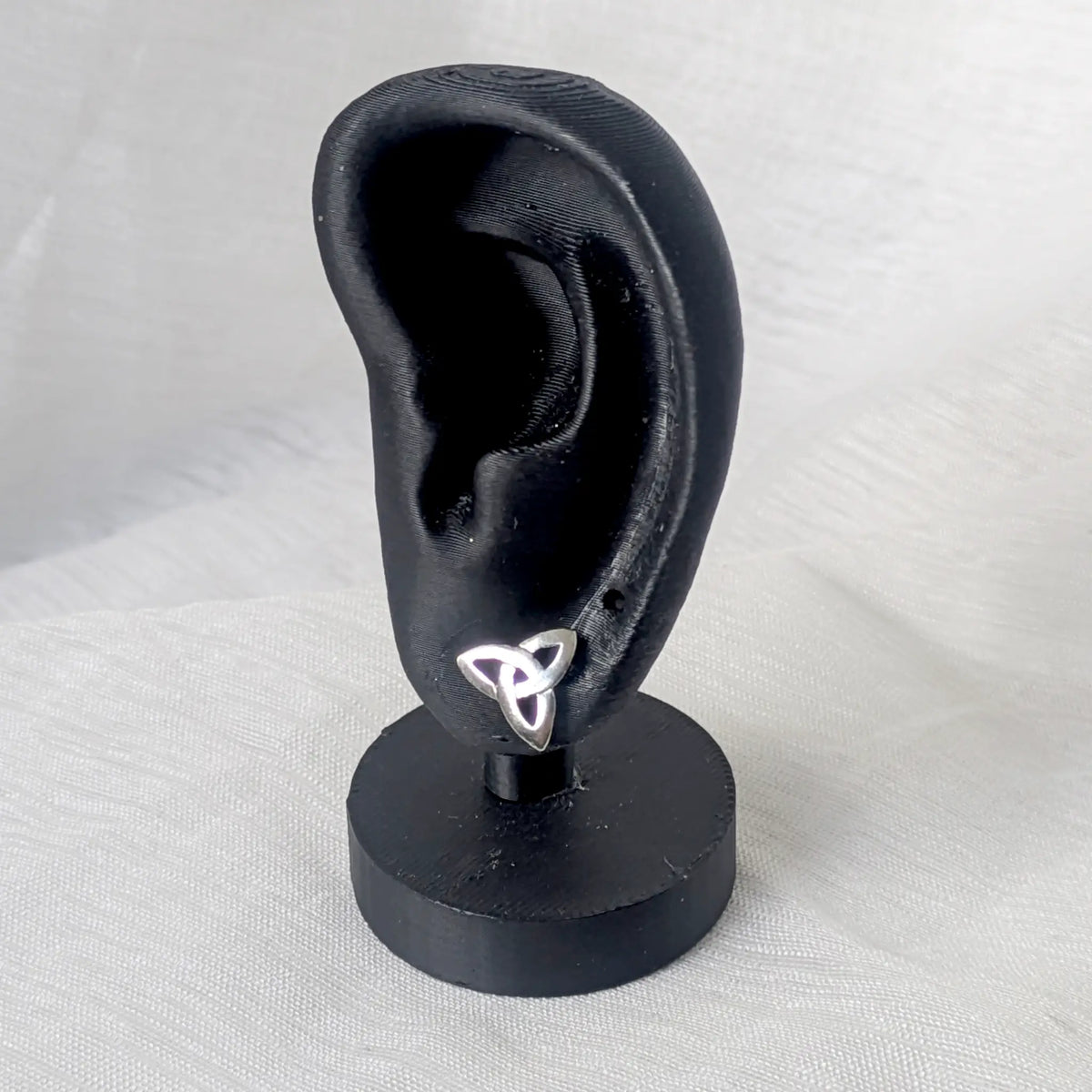 Keltischer Knoten Ohrstecker aus Silber getragen an einem schwarzen Ohr-Display zur Veranschaulichung der dezenten Größe am Ohrläppchen.
