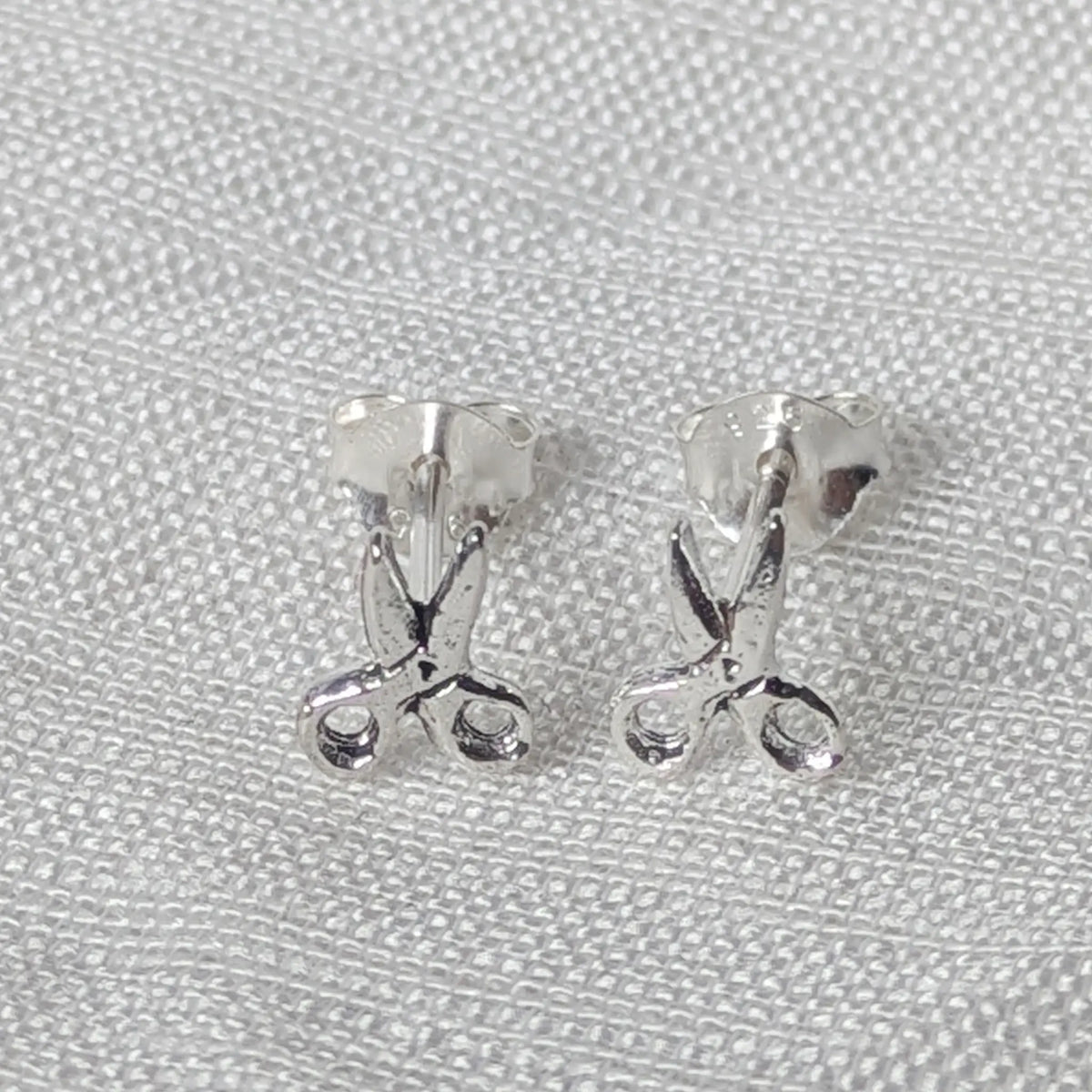Frontalansicht der detaillierten Scheren-Ohrringe aus Silber, die präzise ausgearbeitete Scherenblätter und Griffe zeigt.
