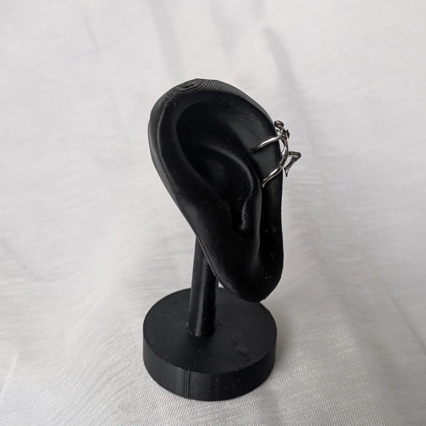 Kletterer Ear Cuff in Trageposition am oberen Ohrrand auf einem schwarzen Display.