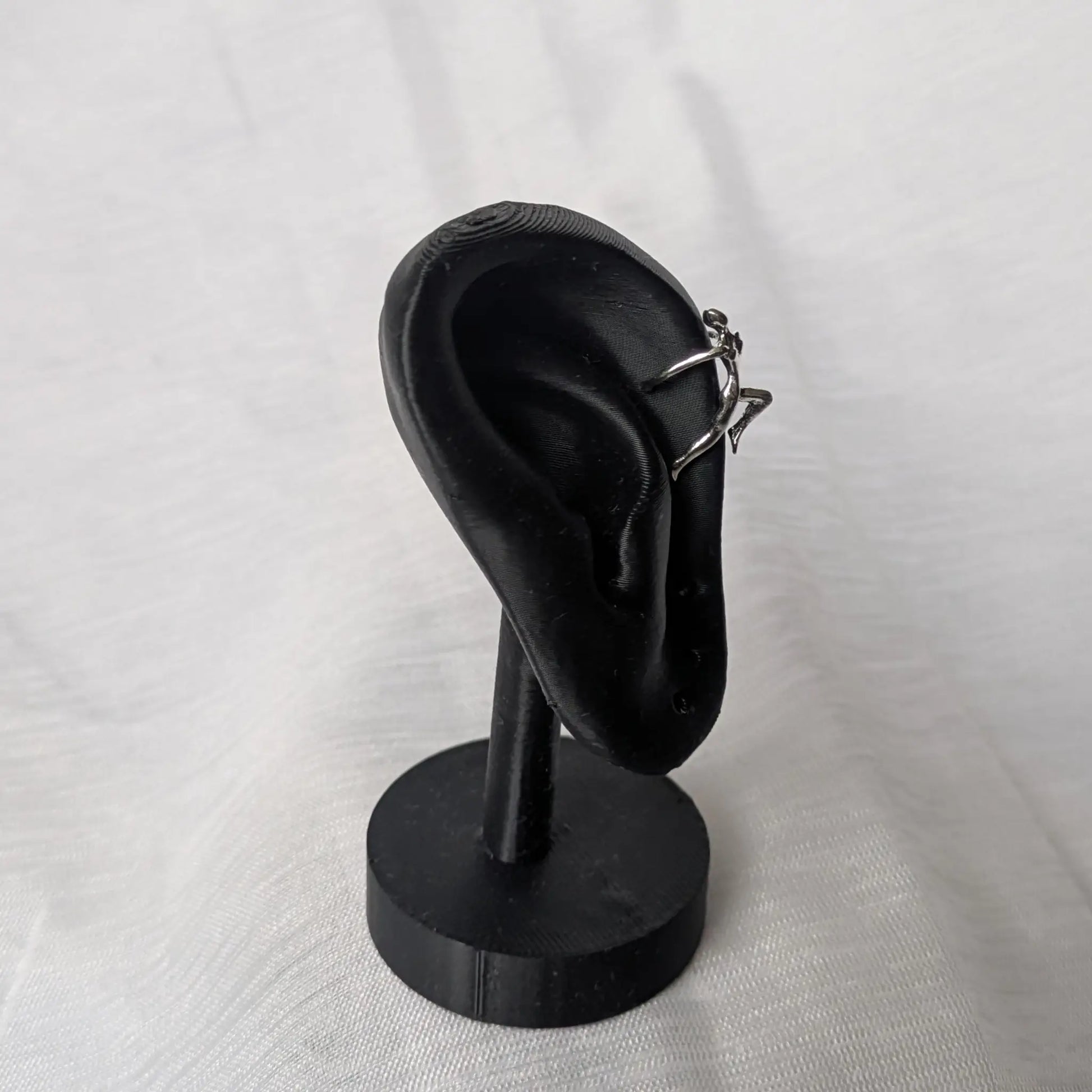 Kletterer Ear Cuff in Trageposition am oberen Ohrrand auf einem schwarzen Display.