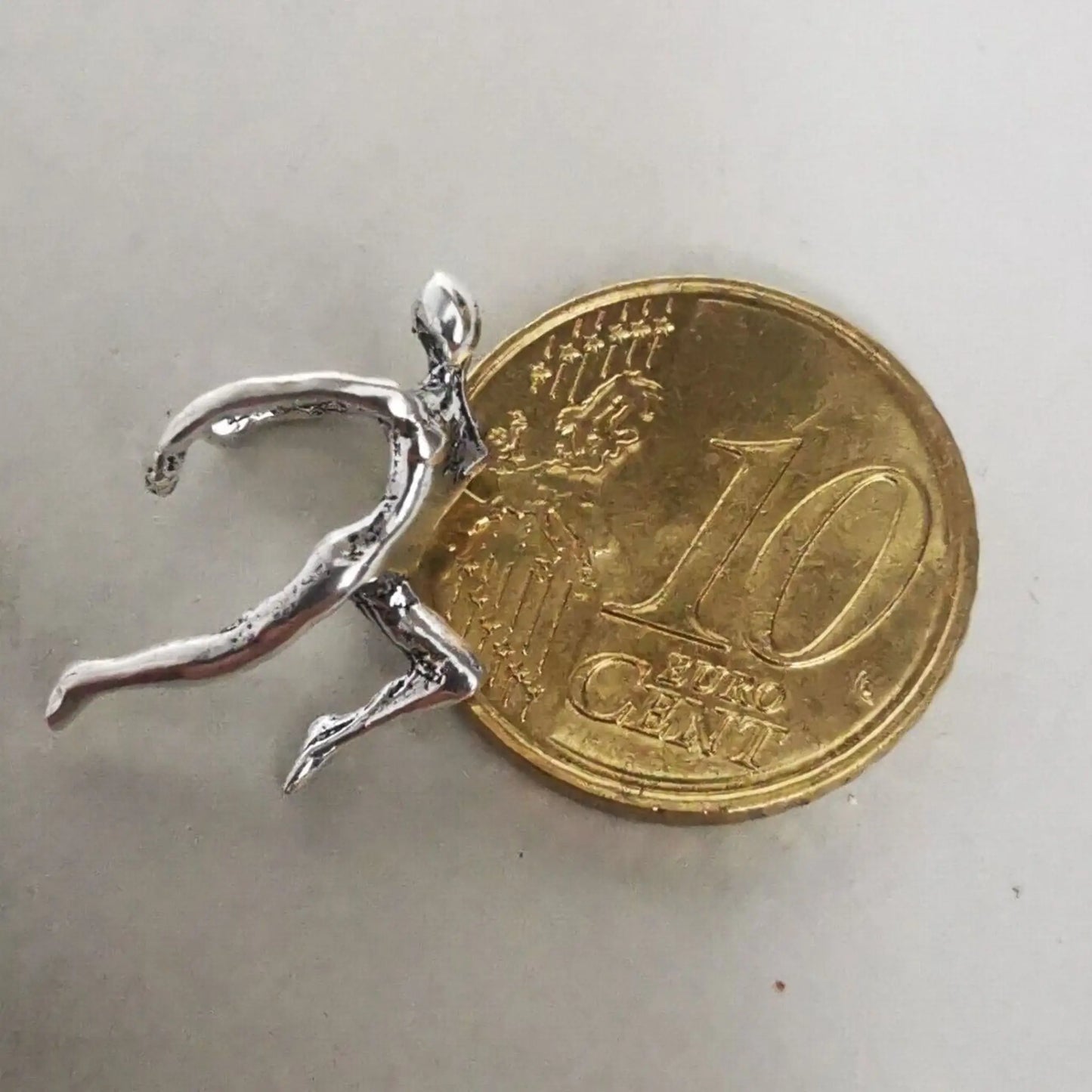 Größenvergleich der filigranen Kletterer-Ohrklemme neben einer 10-Cent-Münze.