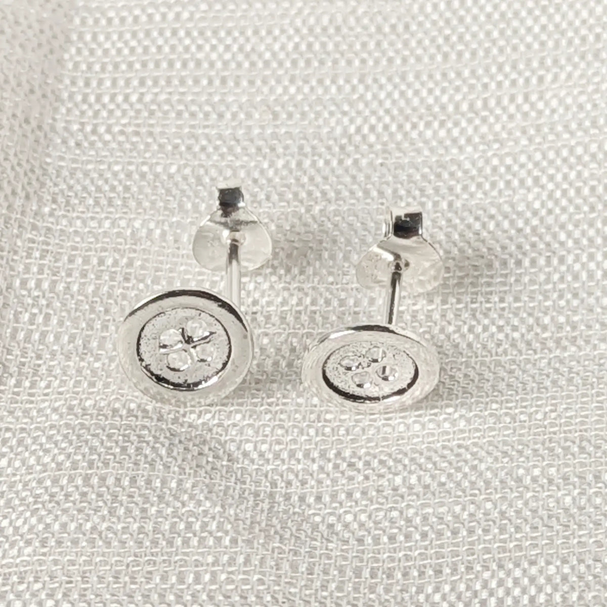 Frontalansicht der runden Silber-Ohrstecker im verspielten Knopf-Design.