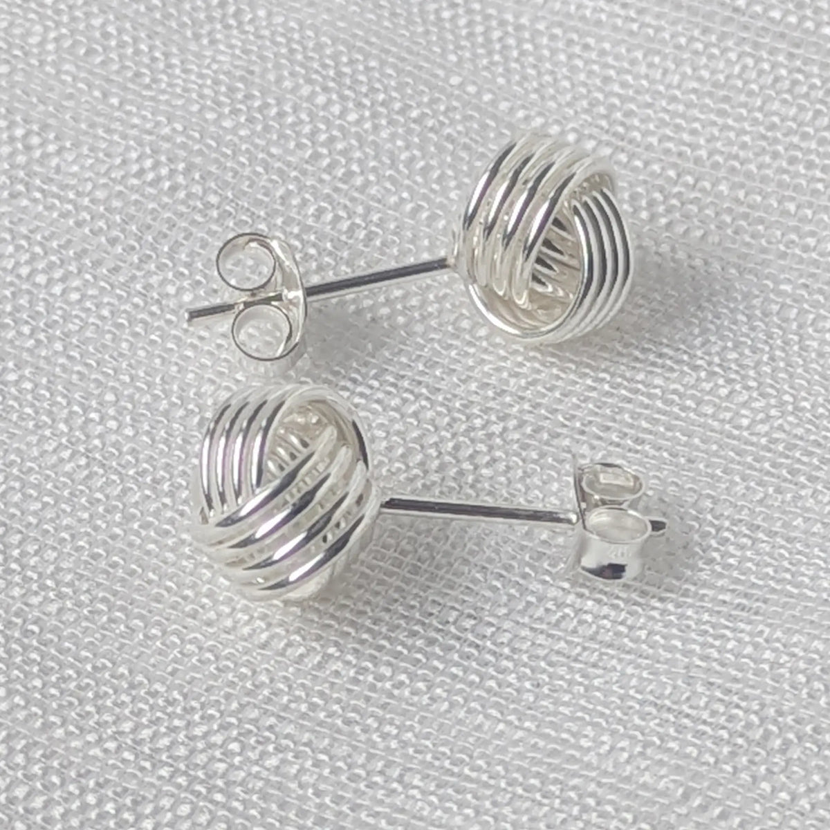 Seitenansicht der massiven Silber-Ohrstecker in Knotenform, welche die plastische, halbkugelförmige Wölbung verdeutlicht.