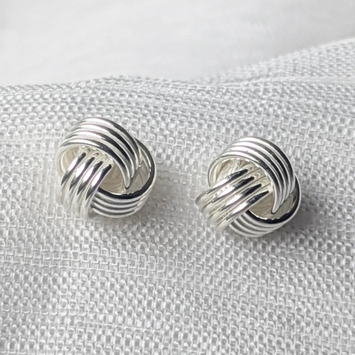 Nahaufnahme der 925 Silber Ohrstecker, die das hochglanzpolierte, mehrreihige Knoten-Design im Detail zeigt.