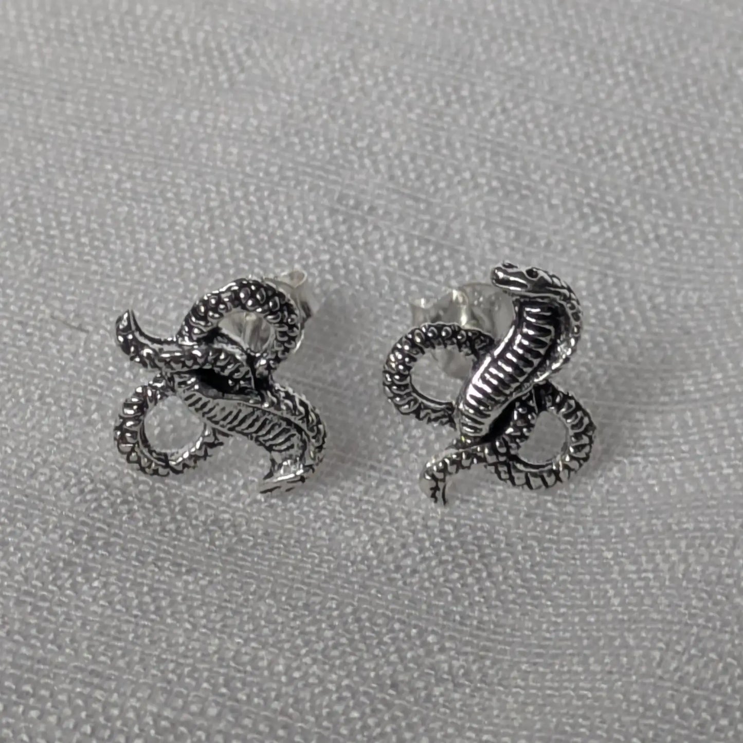 Elegante Kobra Schlangenstecker aus Sterling Silber auf weißem Stoffhintergrund.