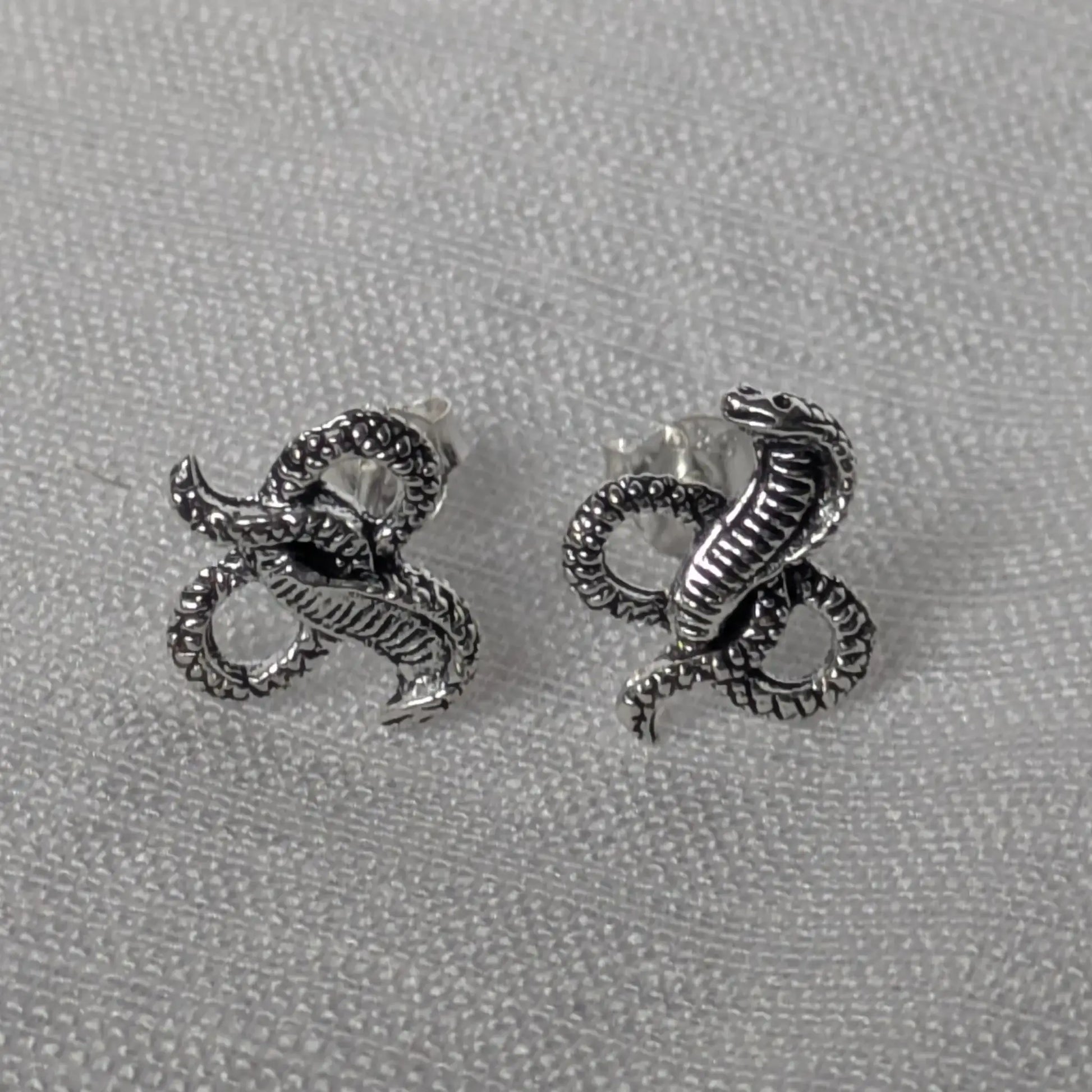 Elegante Kobra Schlangenstecker aus Sterling Silber auf weißem Stoffhintergrund.