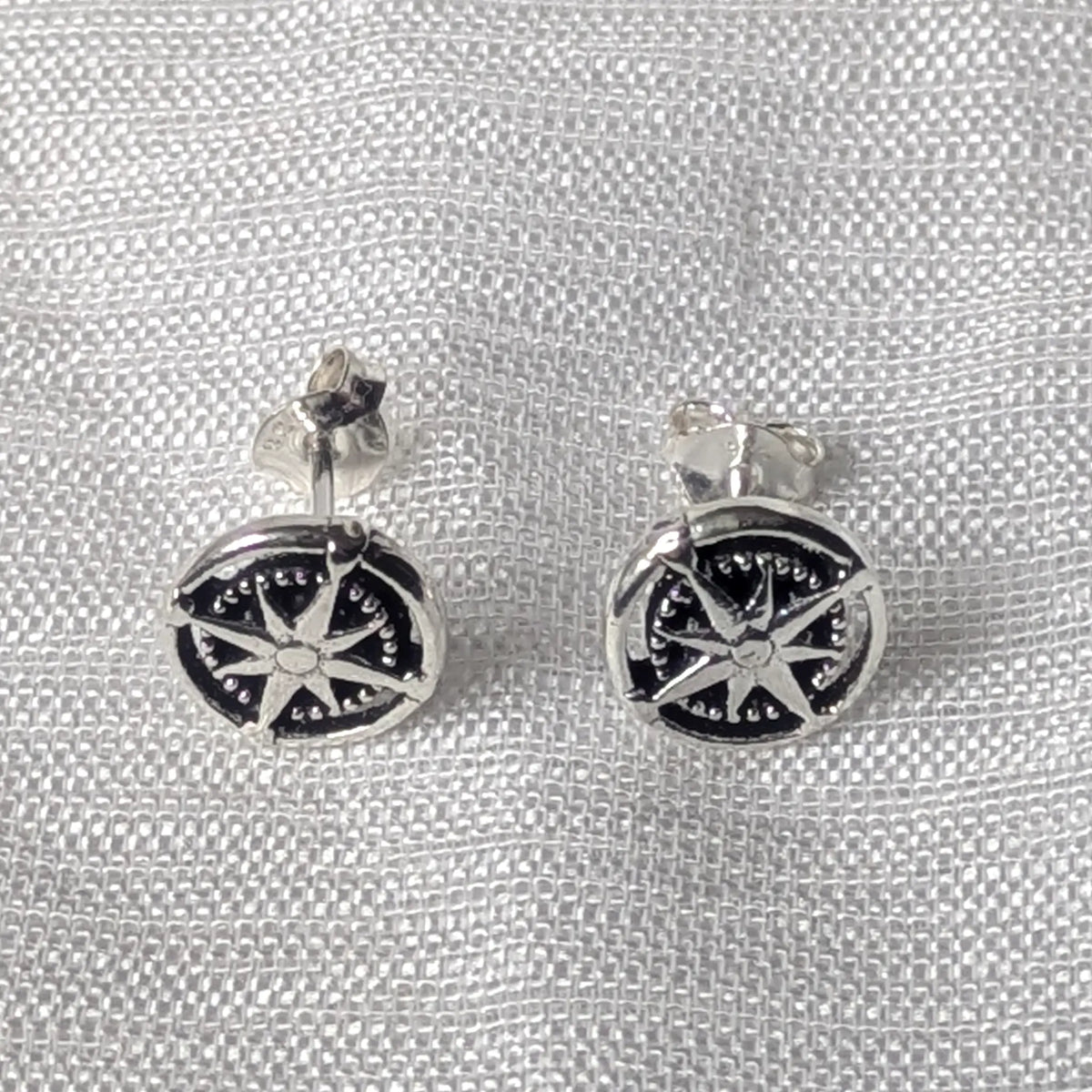 Frontalansicht der maritimen Kompassrose-Ohrstecker aus poliertem und geschwärztem 925 Sterlingsilber.