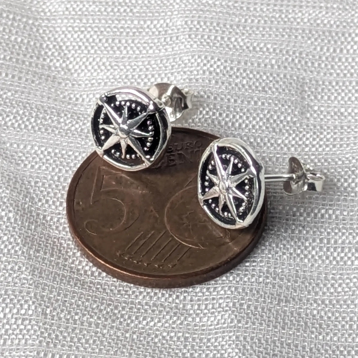 Größenvergleich der zierlichen Kompass-Ohrstecker aus Silber, flach liegend auf einer 5-Cent-Münze.