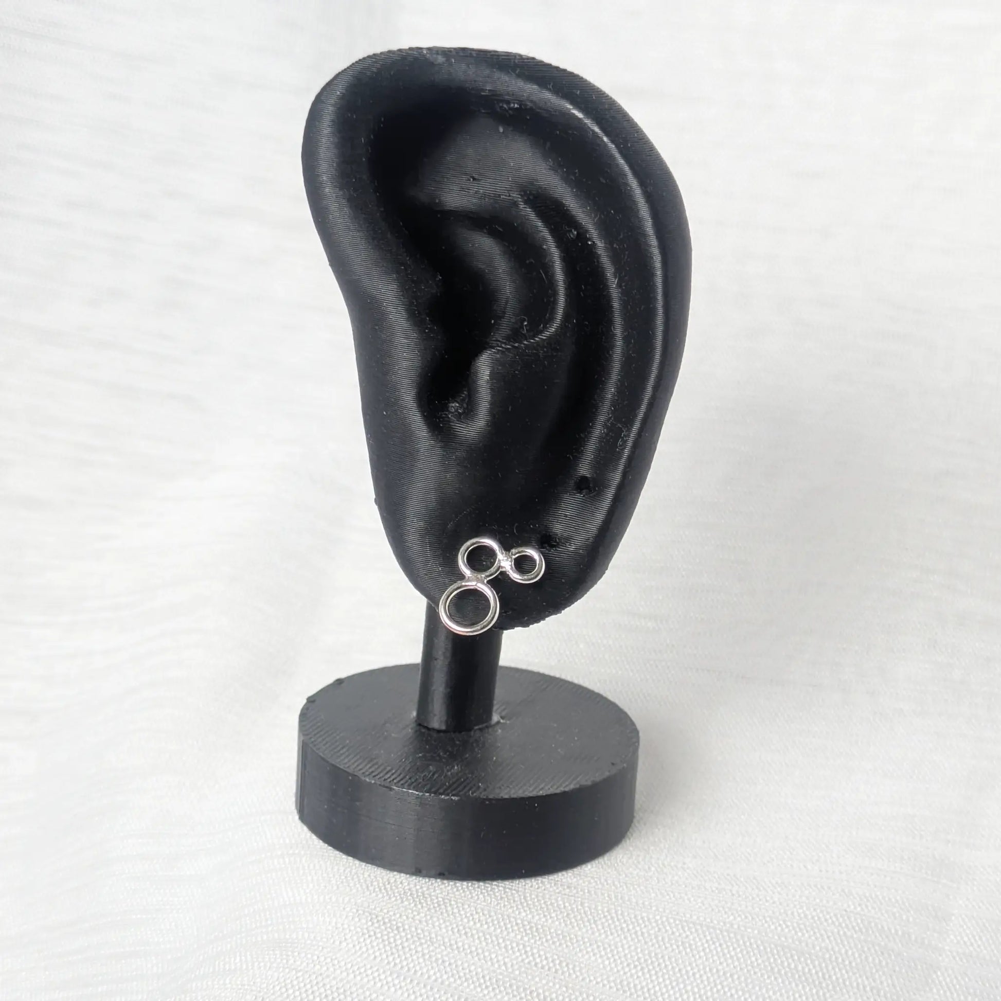 Triple-Ring Silberohrringe präsentiert an einem eleganten schwarzen Display.