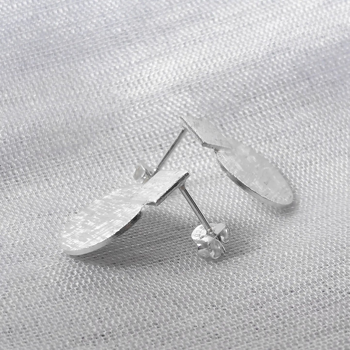 Seitenansicht der strukturierten Geo-Ohrstecker aus Silber zur Darstellung des flachen Designs und des Steckverschlusses.