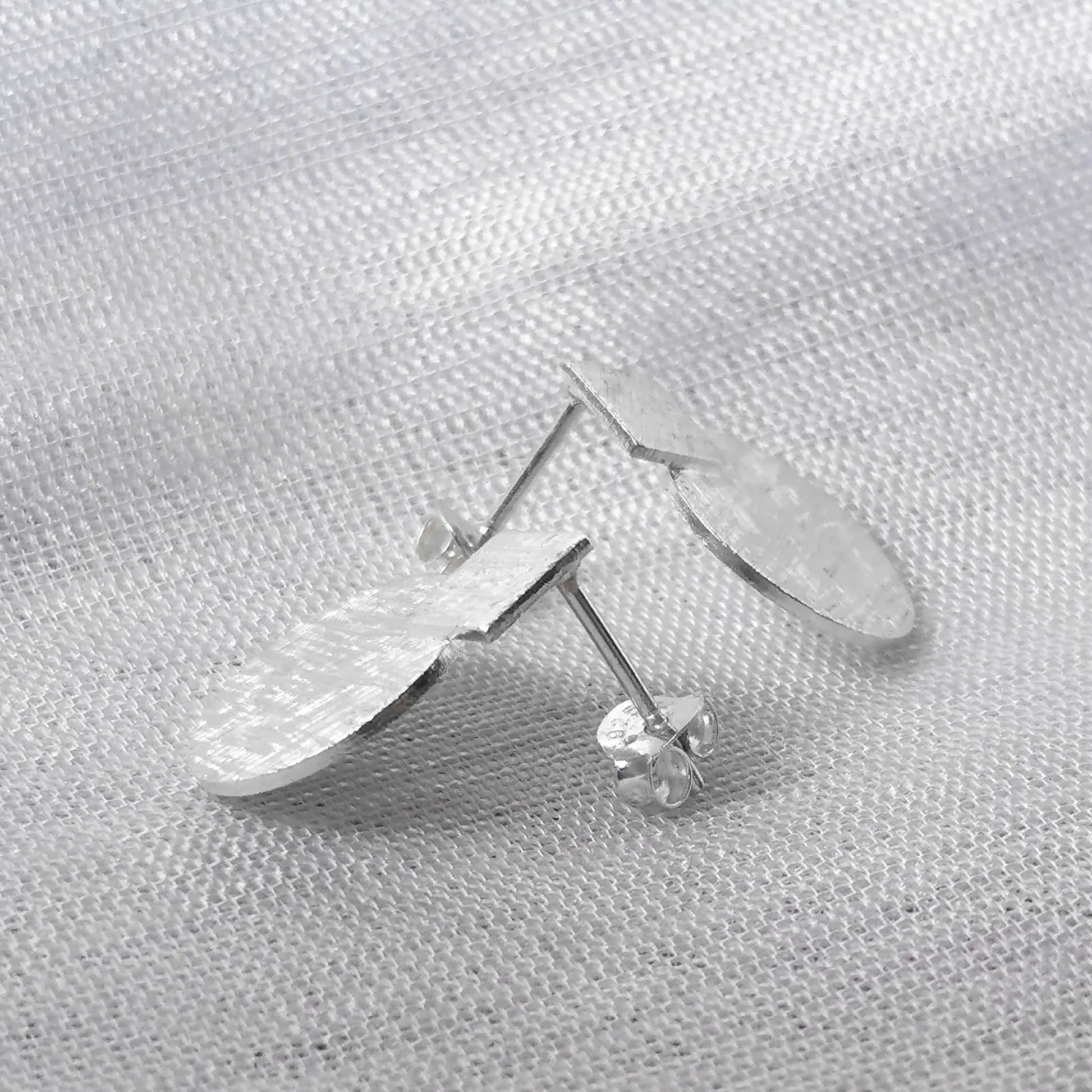Seitenansicht der strukturierten Geo-Ohrstecker aus Silber zur Darstellung des flachen Designs und des Steckverschlusses.