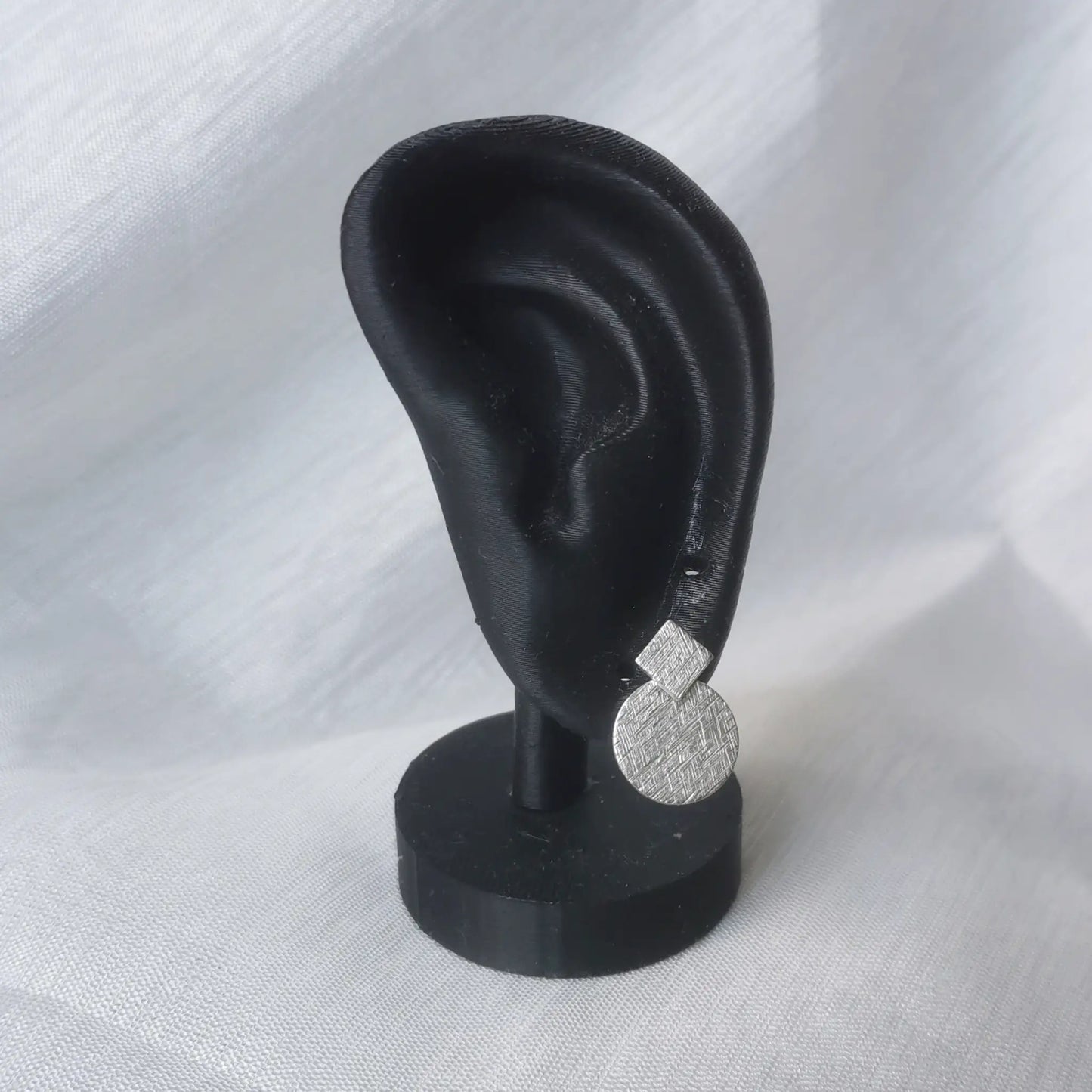 Geometrische Silber-Ohrstecker 925 präsentiert an einem schwarzen Ohr-Modell zur Veranschaulichung von Größe und modernem Look.
