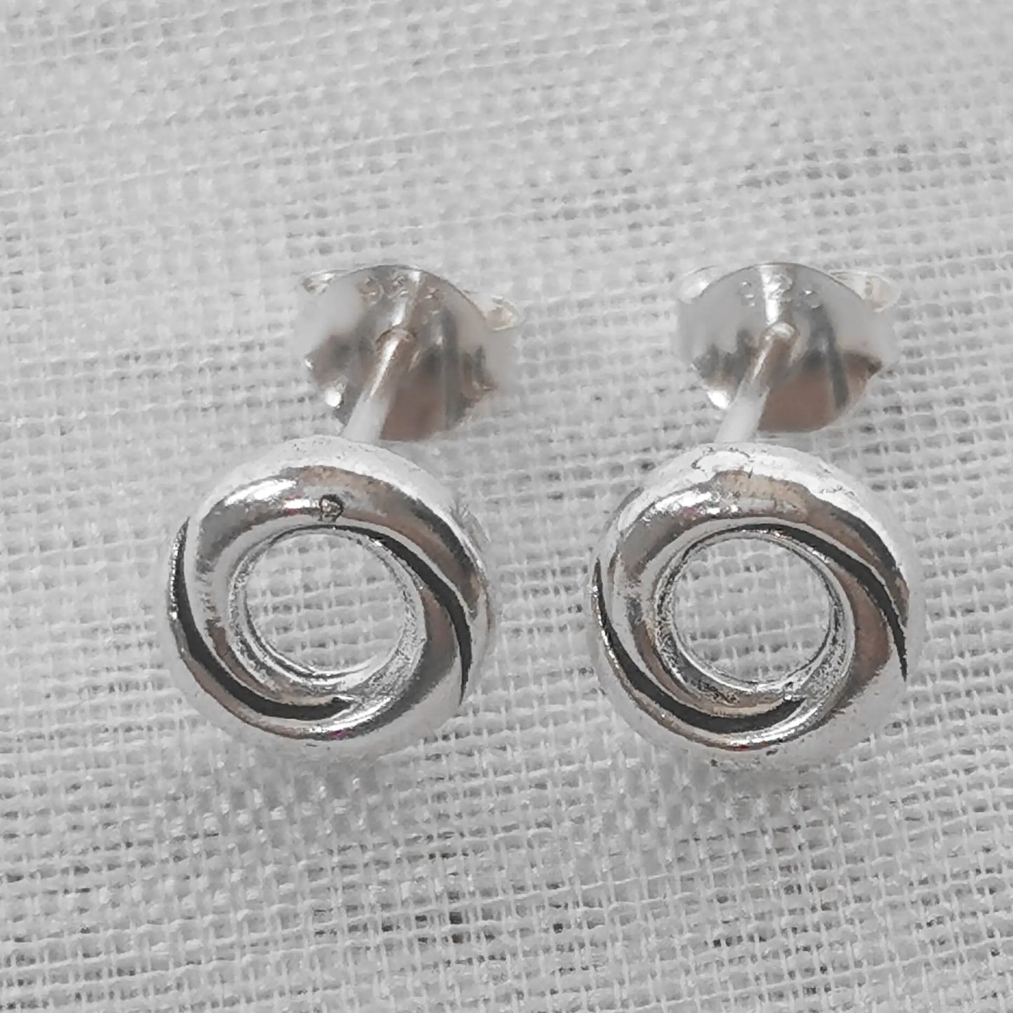 Frontale Ansicht eines Paars kreisförmiger Ohrringe aus glänzendem 925 Sterling Silber im Knoten-Design.