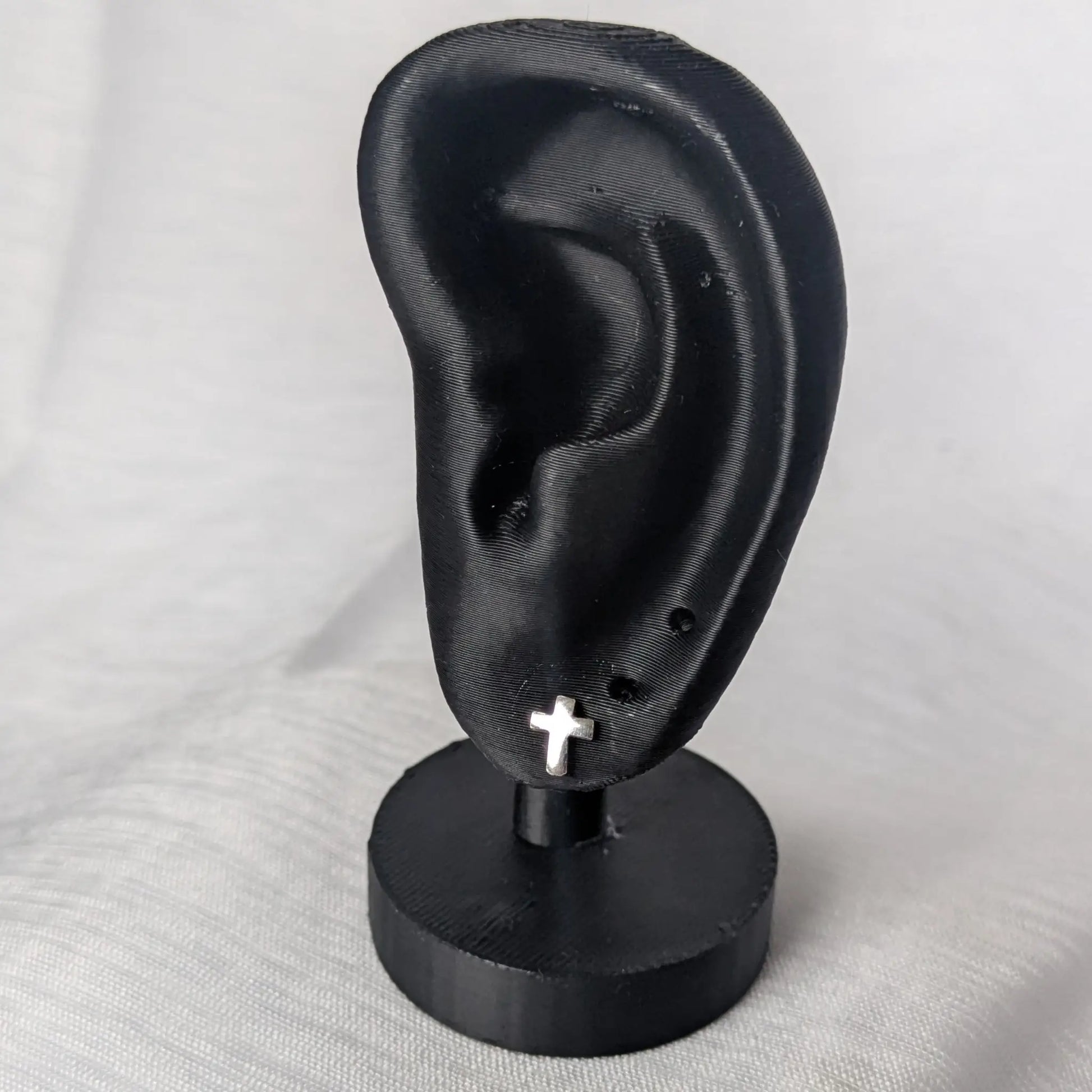 Elegante Präsentation der silbernen Kreuz-Ohrstecker auf schwarzem Samt.