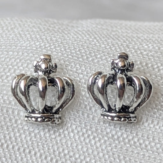 Detailreiche Nahaufnahme von zwei hochglanzpolierten Kronen Ohrsteckern aus 925 Sterling Silber mit geschwärzten Akzenten