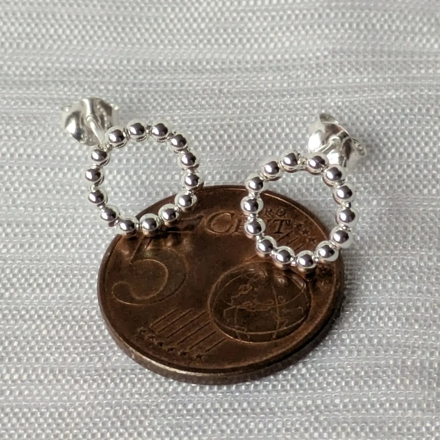 Größenvergleich der minimalistischen Kreis-Ohrringe auf einer 5-Cent-Münze.