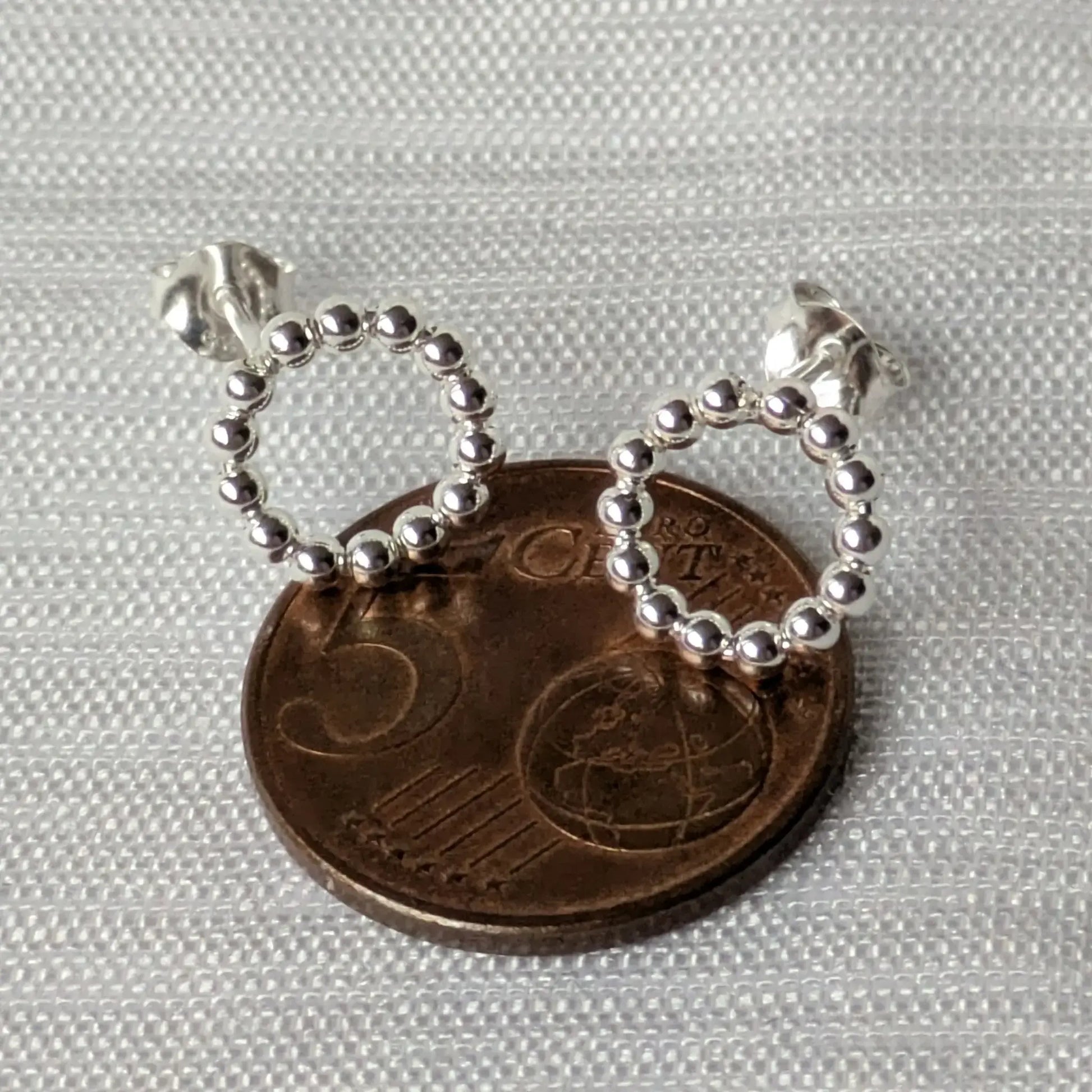 Größenvergleich der minimalistischen Kreis-Ohrringe auf einer 5-Cent-Münze.