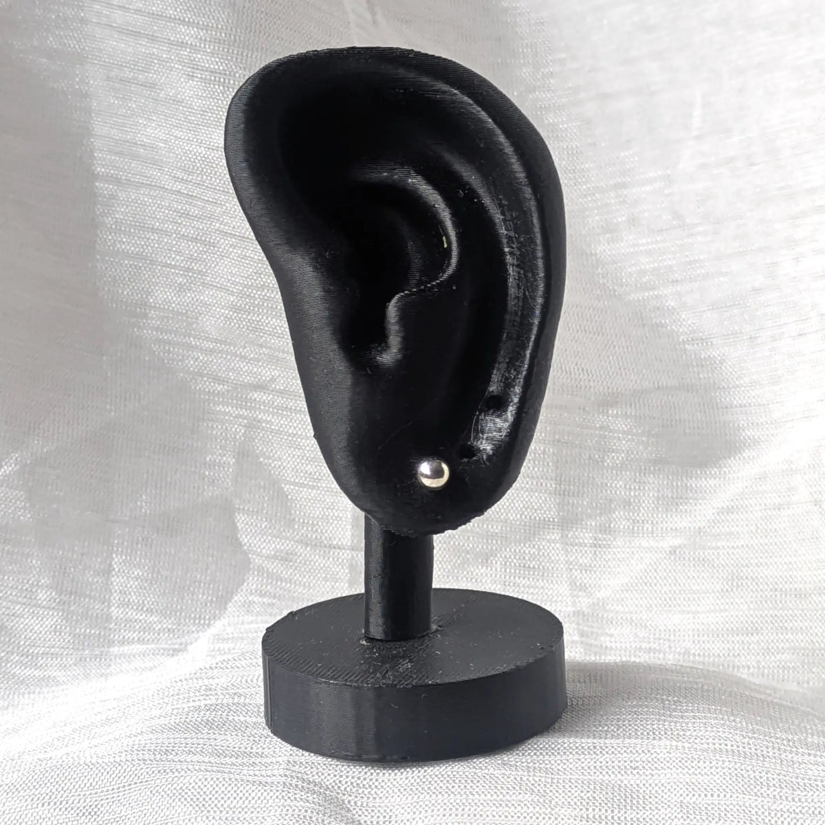 Ein 4mm großer Silber-Kugelohrstecker, dezent und elegant an einem schwarzen 3D-Ohr-Display präsentiert.