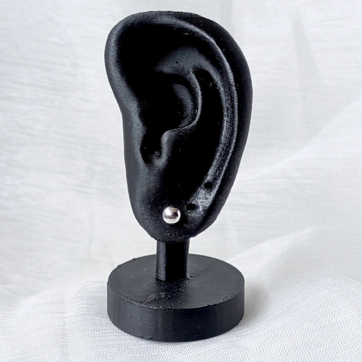 Ein 5mm großer Silber-Kugelohrstecker, dezent und elegant an einem schwarzen 3D-Ohr-Display präsentiert.