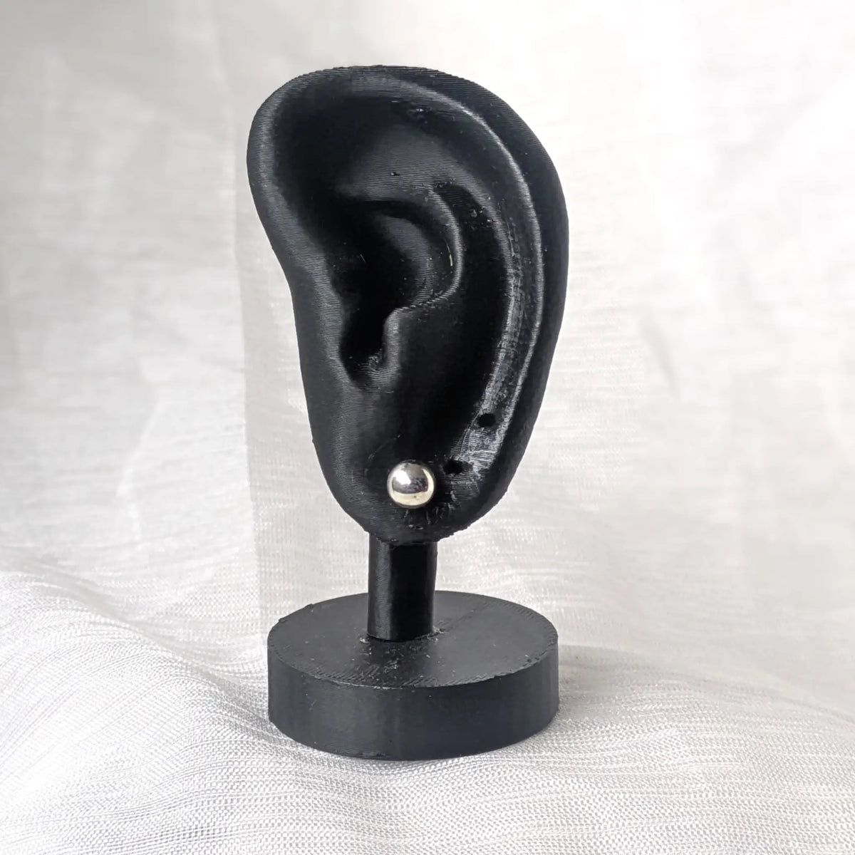 Ein 6mm großer Silber-Kugelohrstecker, dezent und elegant an einem schwarzen 3D-Ohr-Display präsentiert.