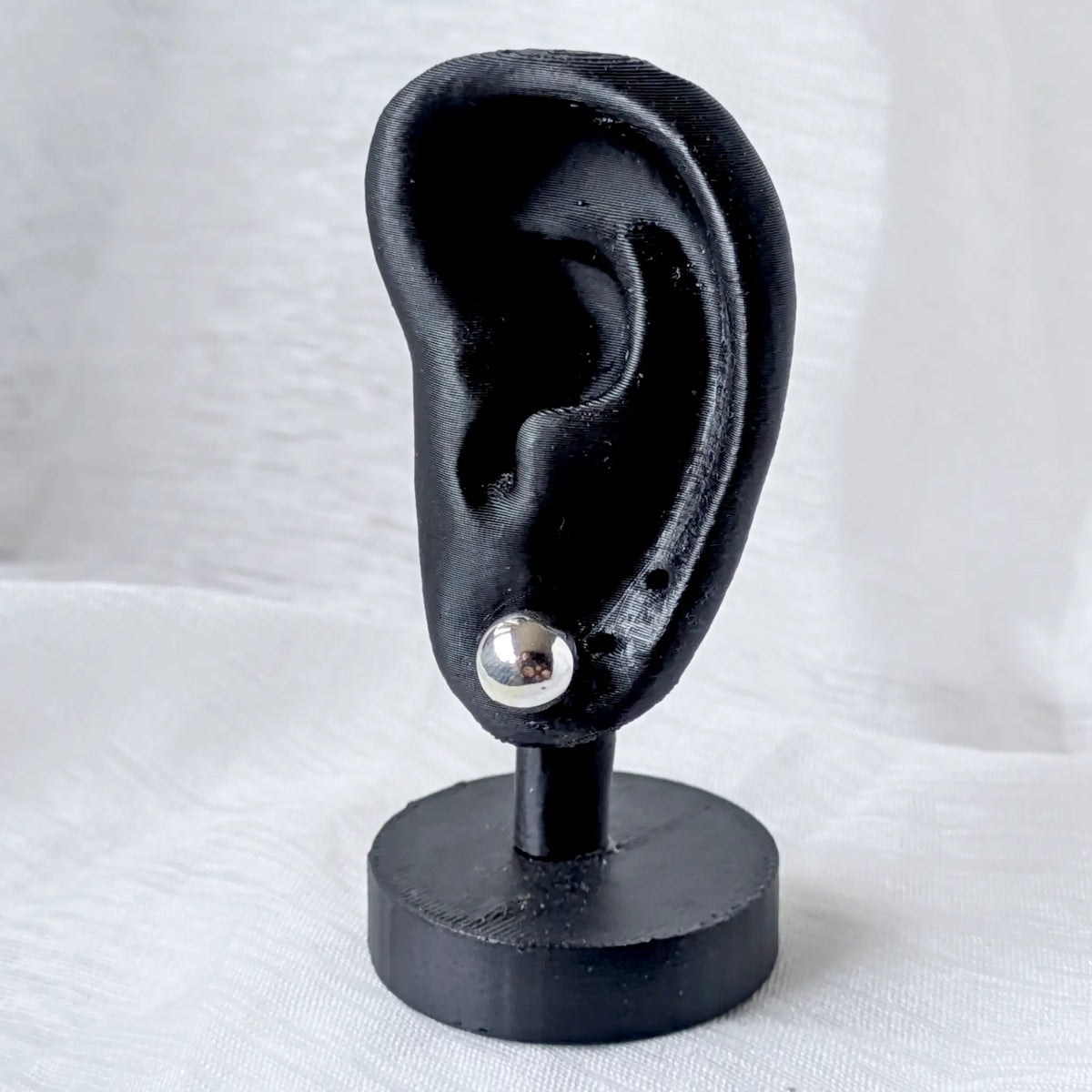 Ein 9mm großer Silber-Kugelohrstecker, dezent und elegant an einem schwarzen 3D-Ohr-Display präsentiert.