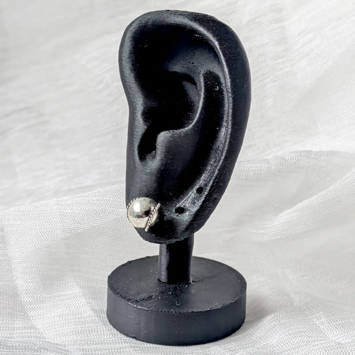 Kugel-Silberohrstecker getragen an einem schwarzen 3D-Ohr-Display zur Veranschaulichung der Größe und Passform.