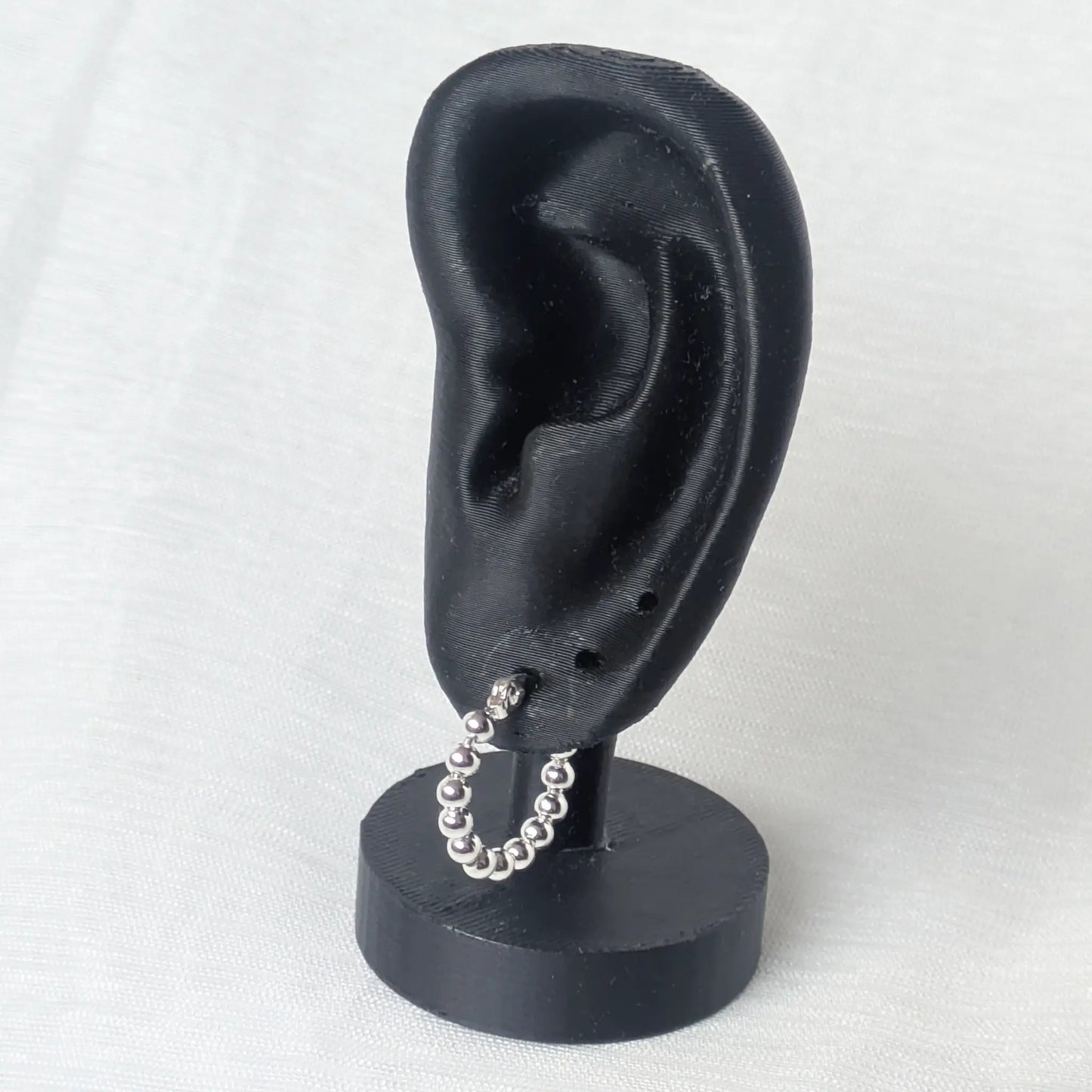 Die kleine 925 Sterling Silber Perlencreole getragen an einem minimalistischen schwarzen Ohr-Display