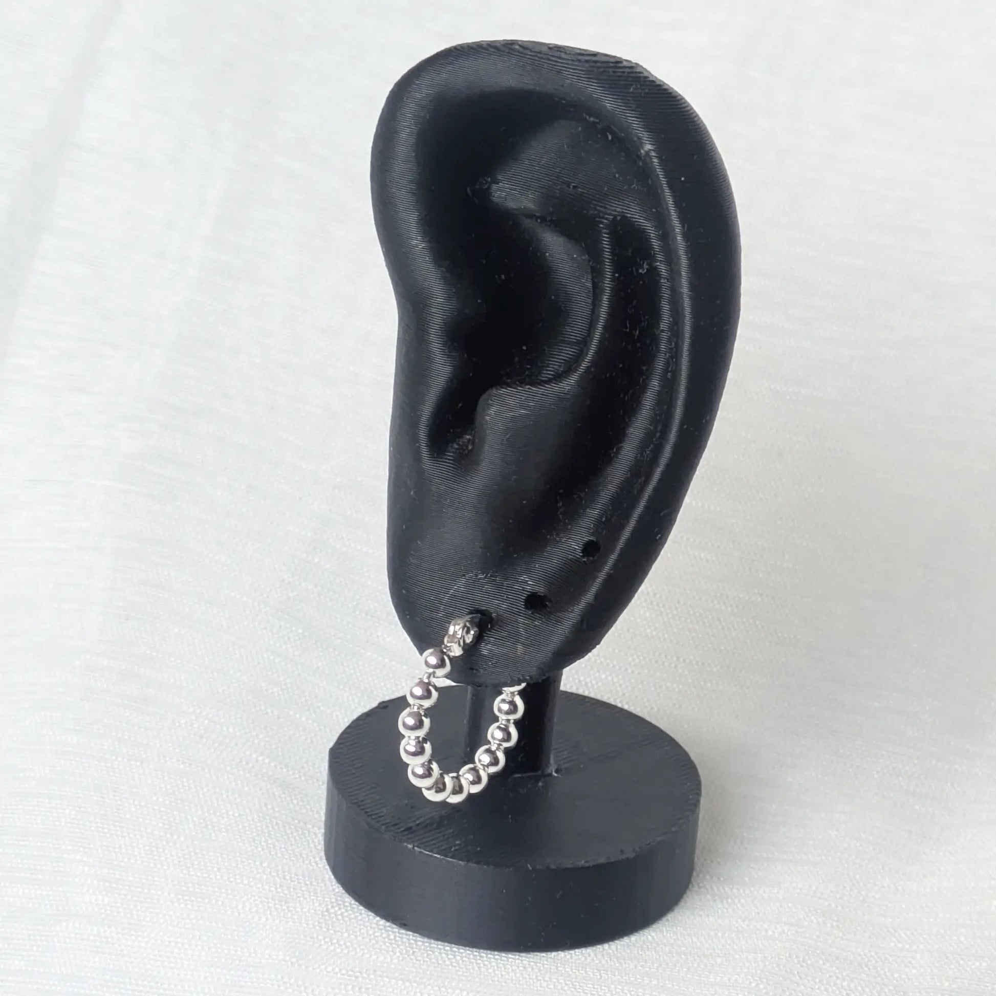 Die kleine 925 Sterling Silber Perlencreole getragen an einem minimalistischen schwarzen Ohr-Display
