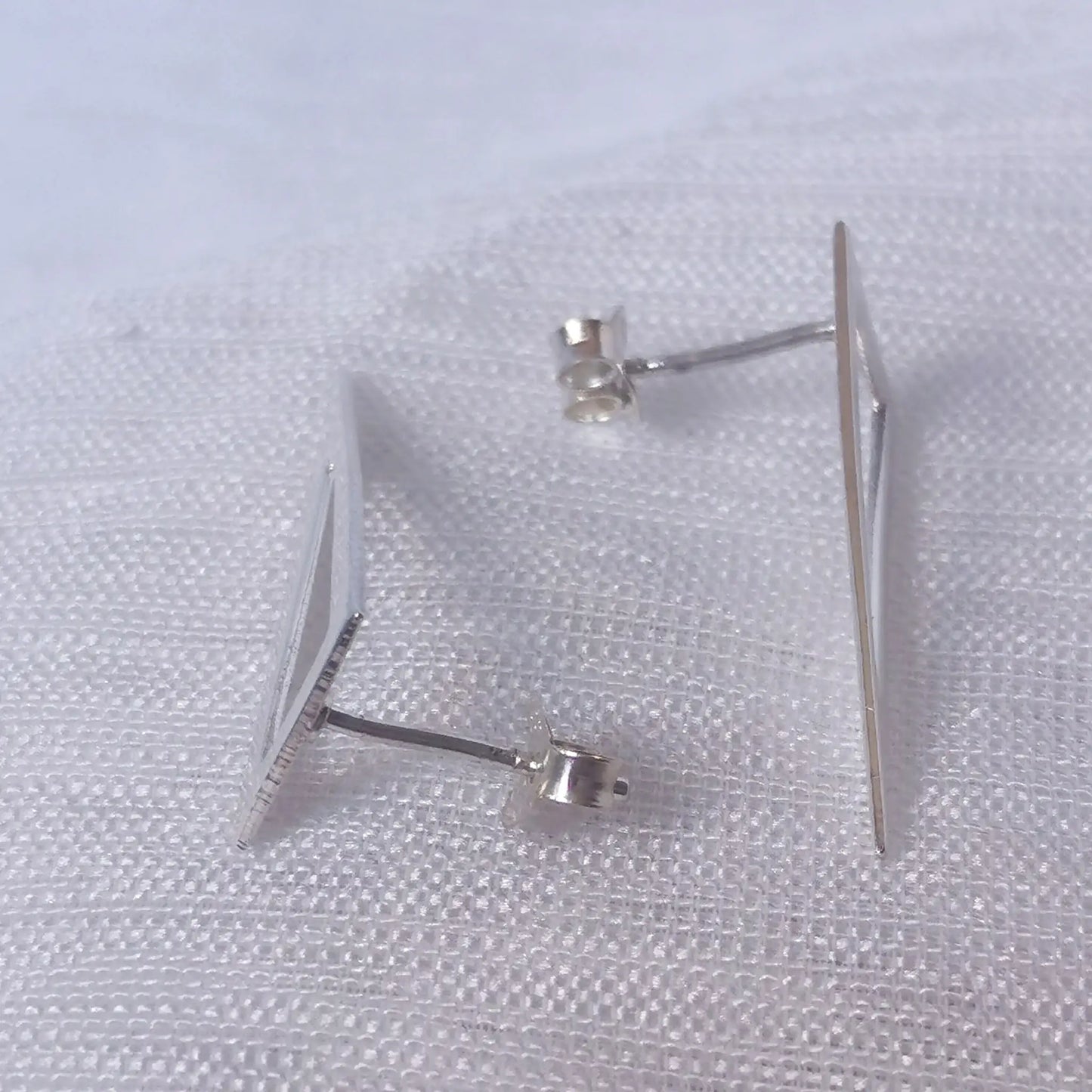 Seitenansicht der langen Triangel-Ohrstecker zur Veranschaulichung des flachen Profils und der exakten Stift-Positionierung.
