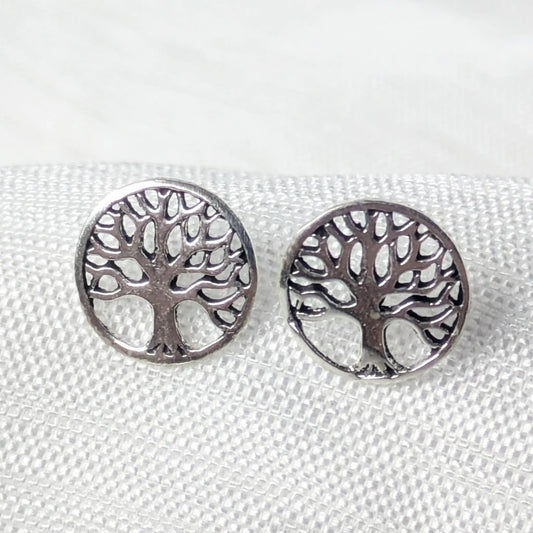 Nahaufnahme von einem Paar runder 925 Silber-Ohrstecker mit filigranem Lebensbaum-Motiv auf weißem Strukturstoff.