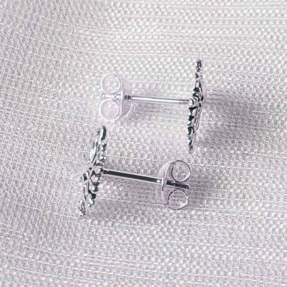 Seitliche Perspektive der flach gearbeiteten Lebensbaum-Ohrstecker aus echtem Silber.