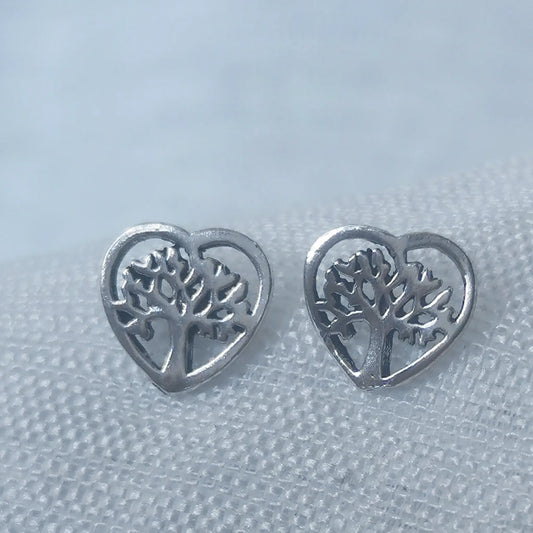 Nahaufnahme von zwei herzförmigen Ohrsteckern aus 925 Silber mit filigran eingearbeitetem Lebensbaum-Motiv.