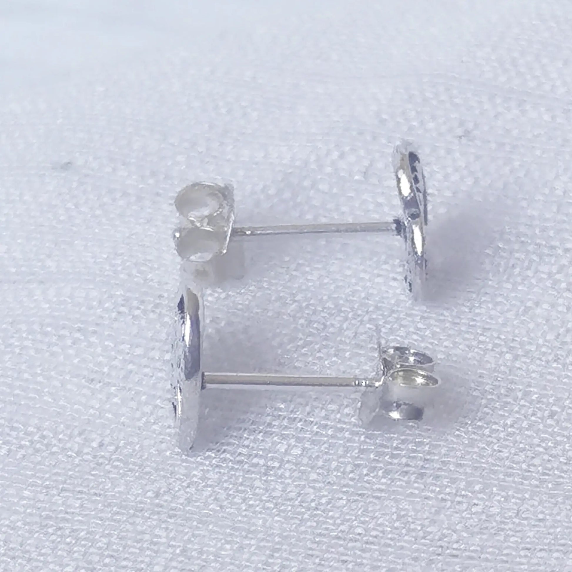 Seitenansicht der Symbol-Ohrstecker aus Echtsilber zur Ansicht der flachen, komfortablen Form und des Ohrstifts.