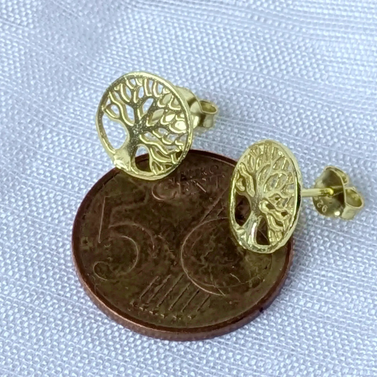 Größenvergleich der kleinen Lebensbaum-Ohrstecker liegend auf einer 5-Cent-Münze zur exakten Darstellung der kompakten Größe