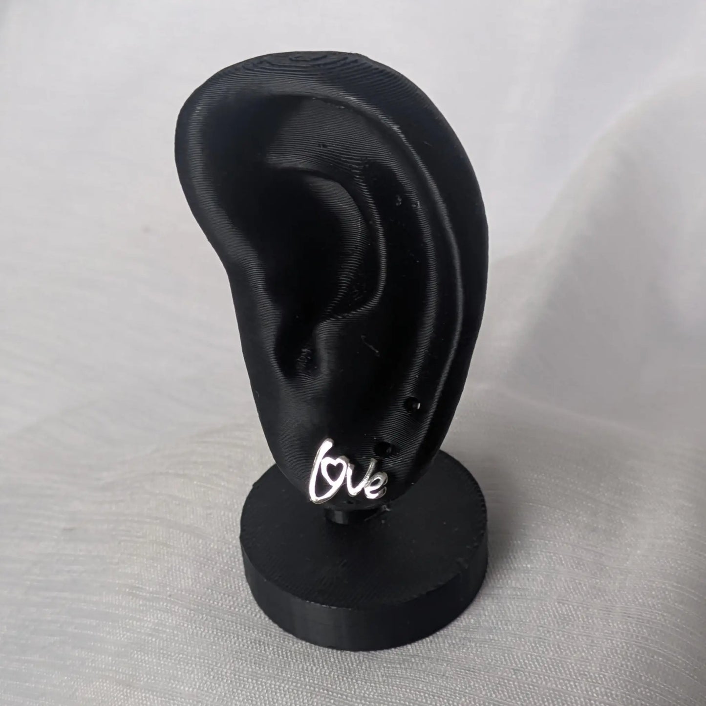 Filigrane Love-Ohrringe an einem Schmuck-Display zur Veranschaulichung der Größe am Ohrläppchen.