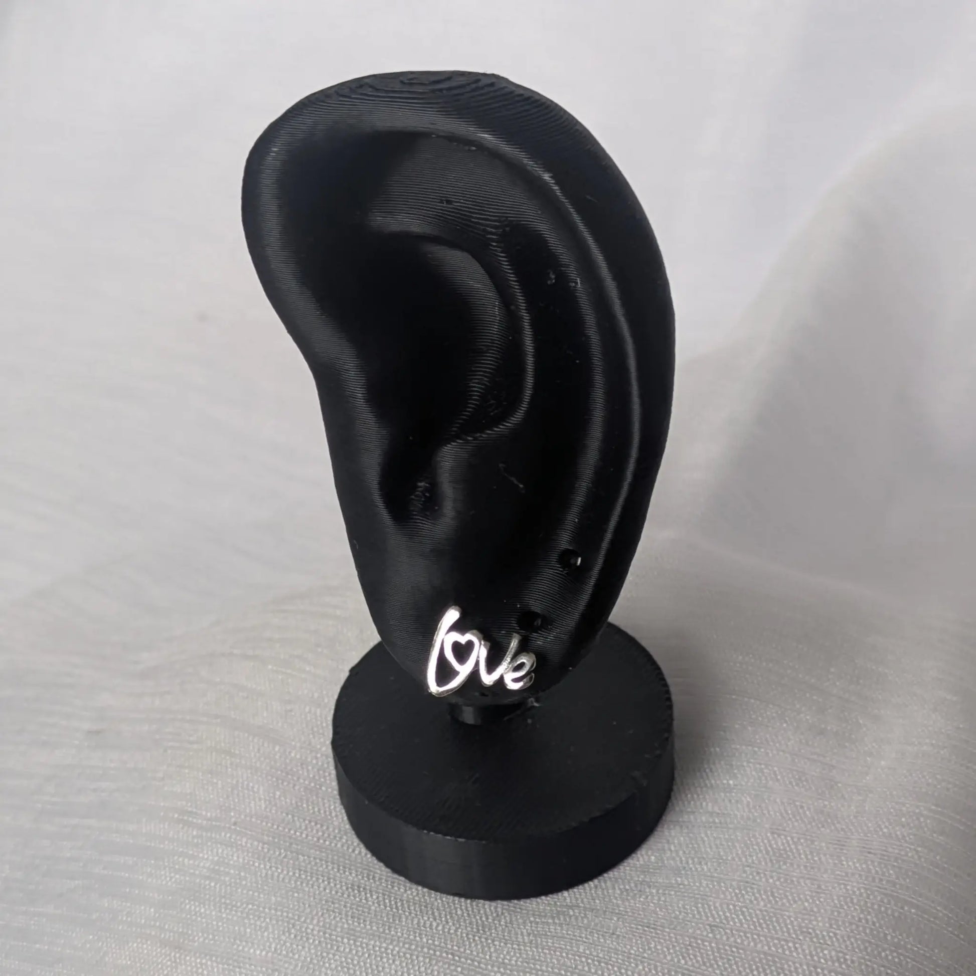 Filigrane Love-Ohrringe an einem Schmuck-Display zur Veranschaulichung der Größe am Ohrläppchen.