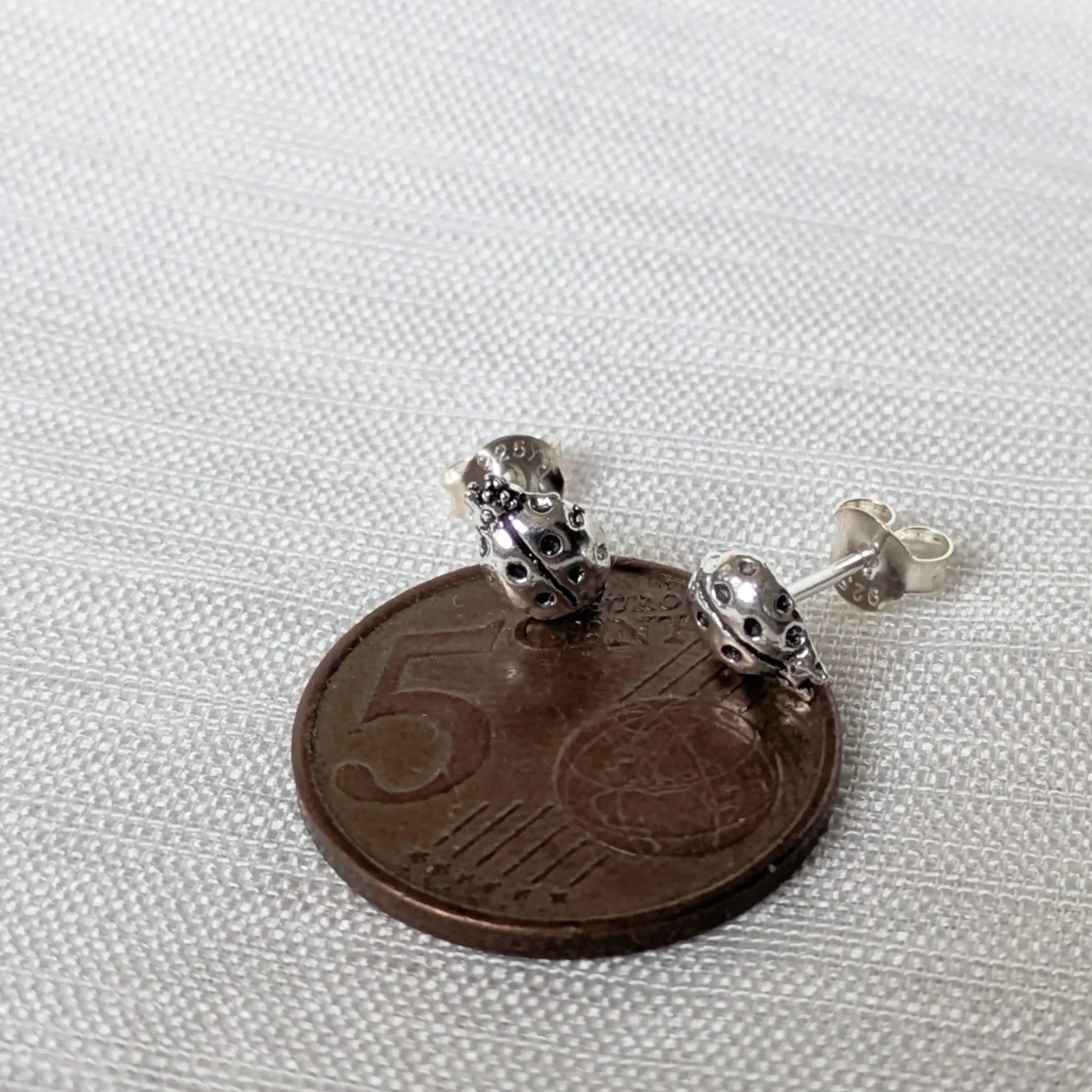 Größenvergleich: Marienkäfer Ohrringe aus Silber auf einer 5-Cent-Münze.