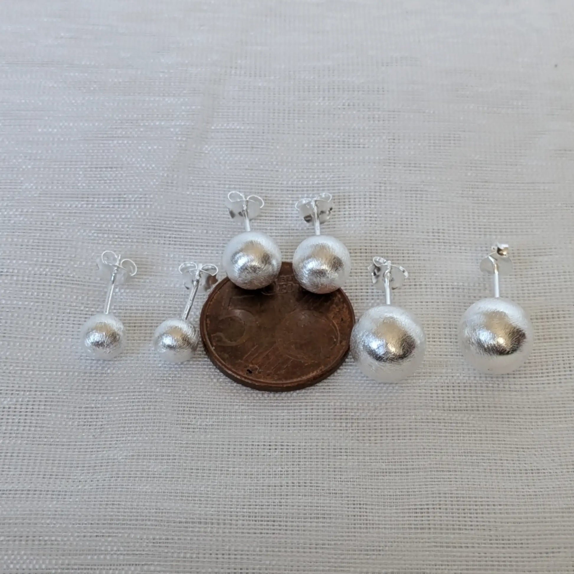 Größenvergleich der 925 Silber Kugelohrringe neben einer 5-Cent-Münze.