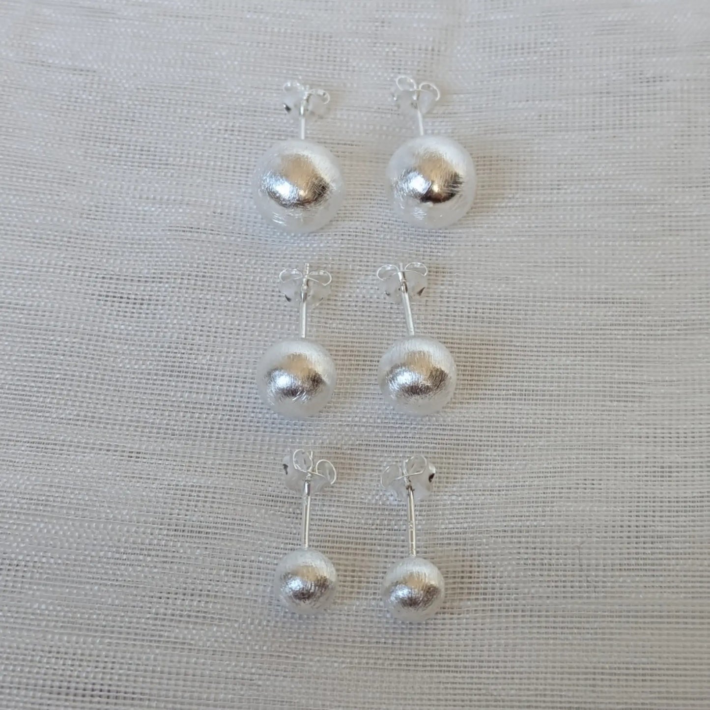 Frontalansicht der silbernen 6mm, 8mm und 10mm Kugelohrringe mit gebürsteter Oberfläche.