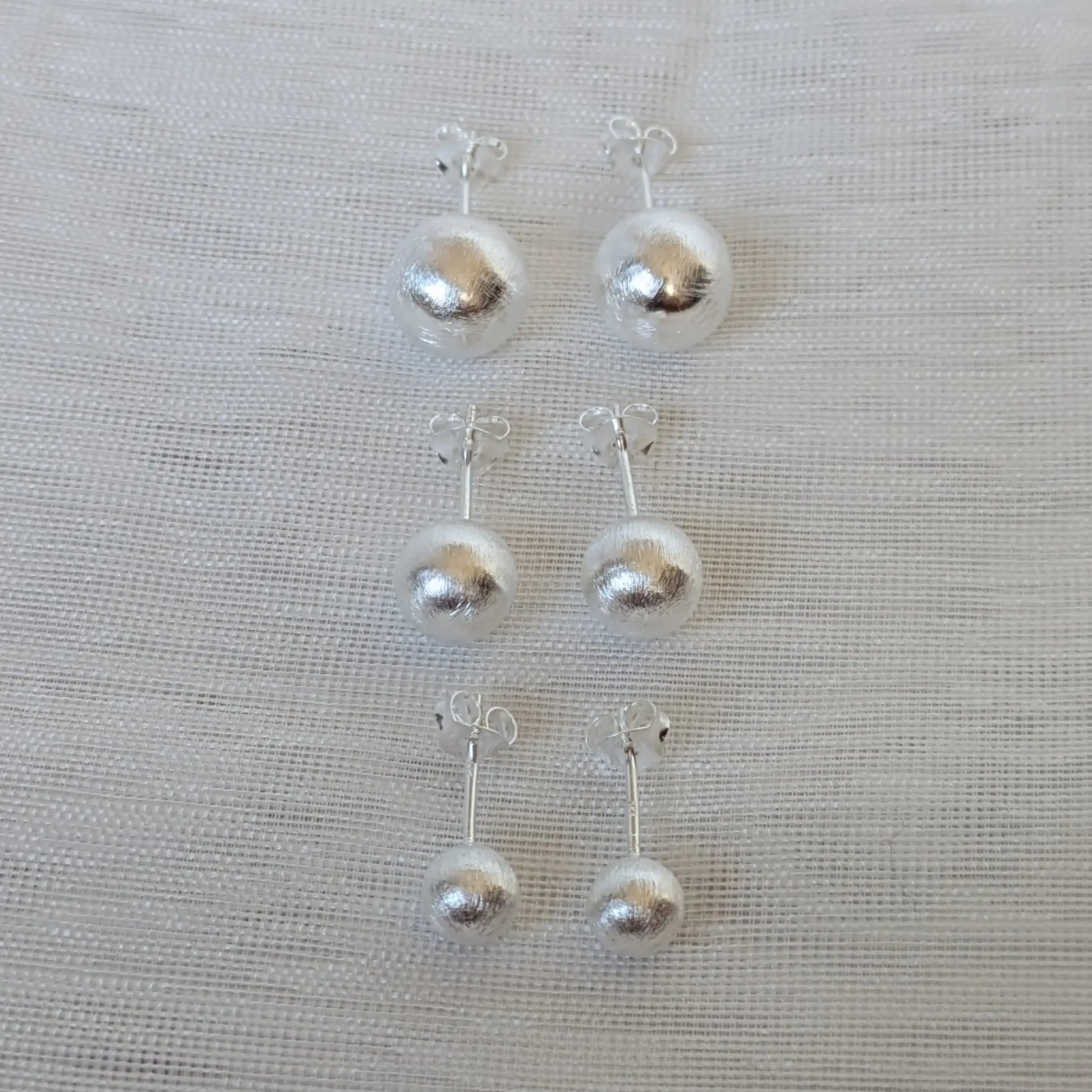 Frontalansicht der silbernen 6mm, 8mm und 10mm Kugelohrringe mit gebürsteter Oberfläche.