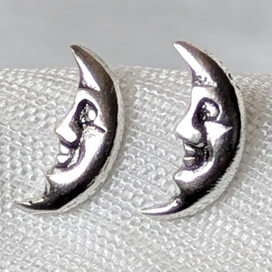Nahaufnahme von zwei filigranen Mondgesicht-Ohrsteckern aus glänzendem 925 Silber mit detaillierten Gesichtern.