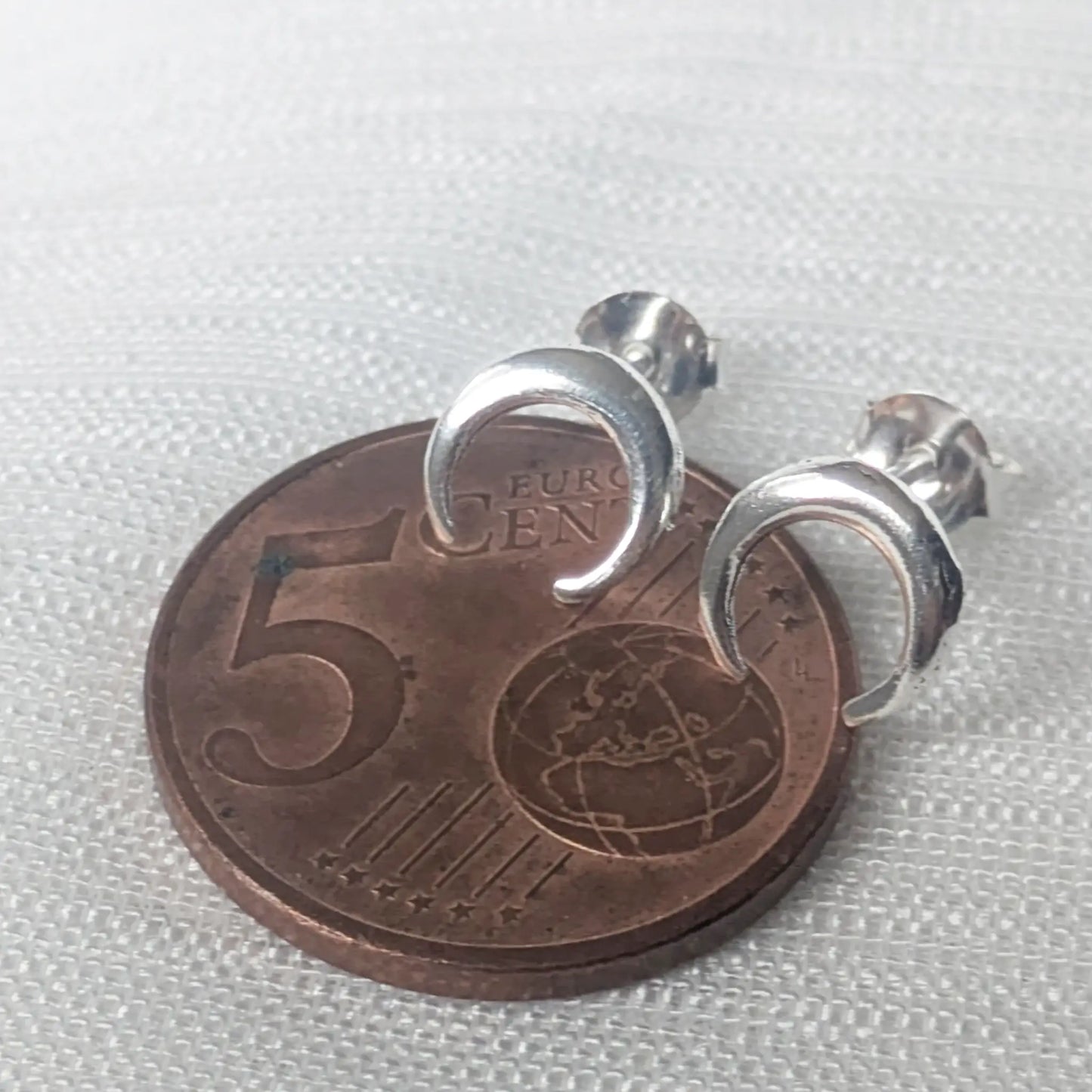 Größenvergleich: Die schlichten Crescent-Mondohrringe aus Silber auf einer 5-Cent-Münze zur exakten Verdeutlichung der zierlichen Maße.