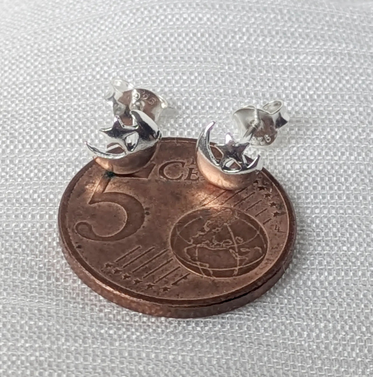 Größenvergleich: Zierliche Mond-Stern Ohrstecker aus hochglanzpoliertem Silber liegend auf einer 5-Cent-Münze