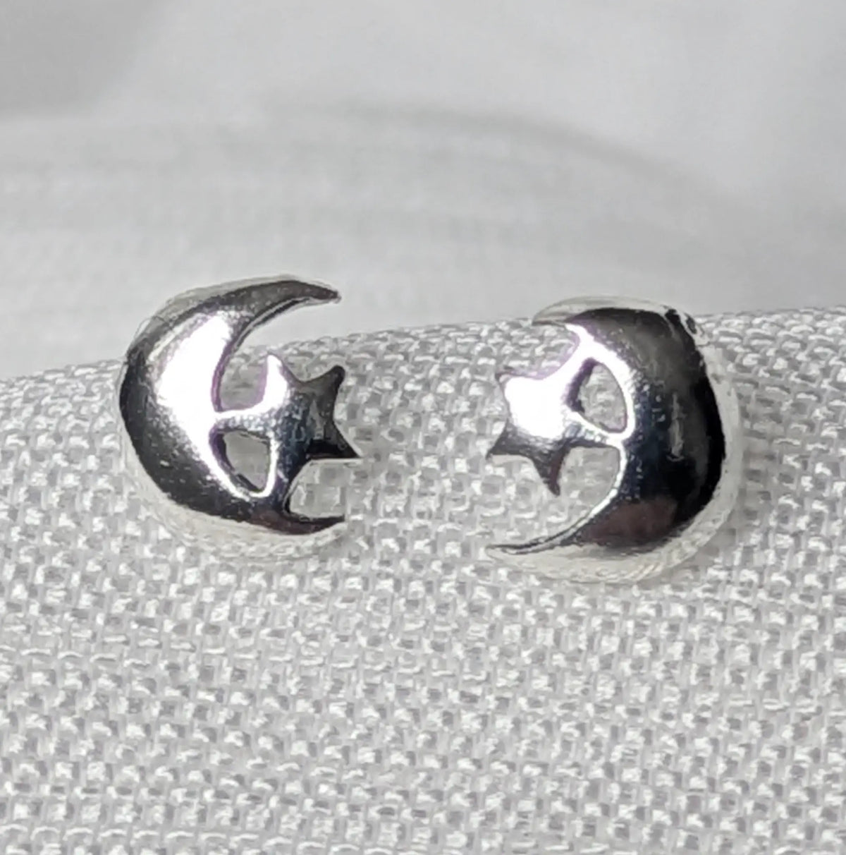 Nahaufnahme von filigranen 925 Silber Ohrsteckern im glänzenden Mond und Stern Design