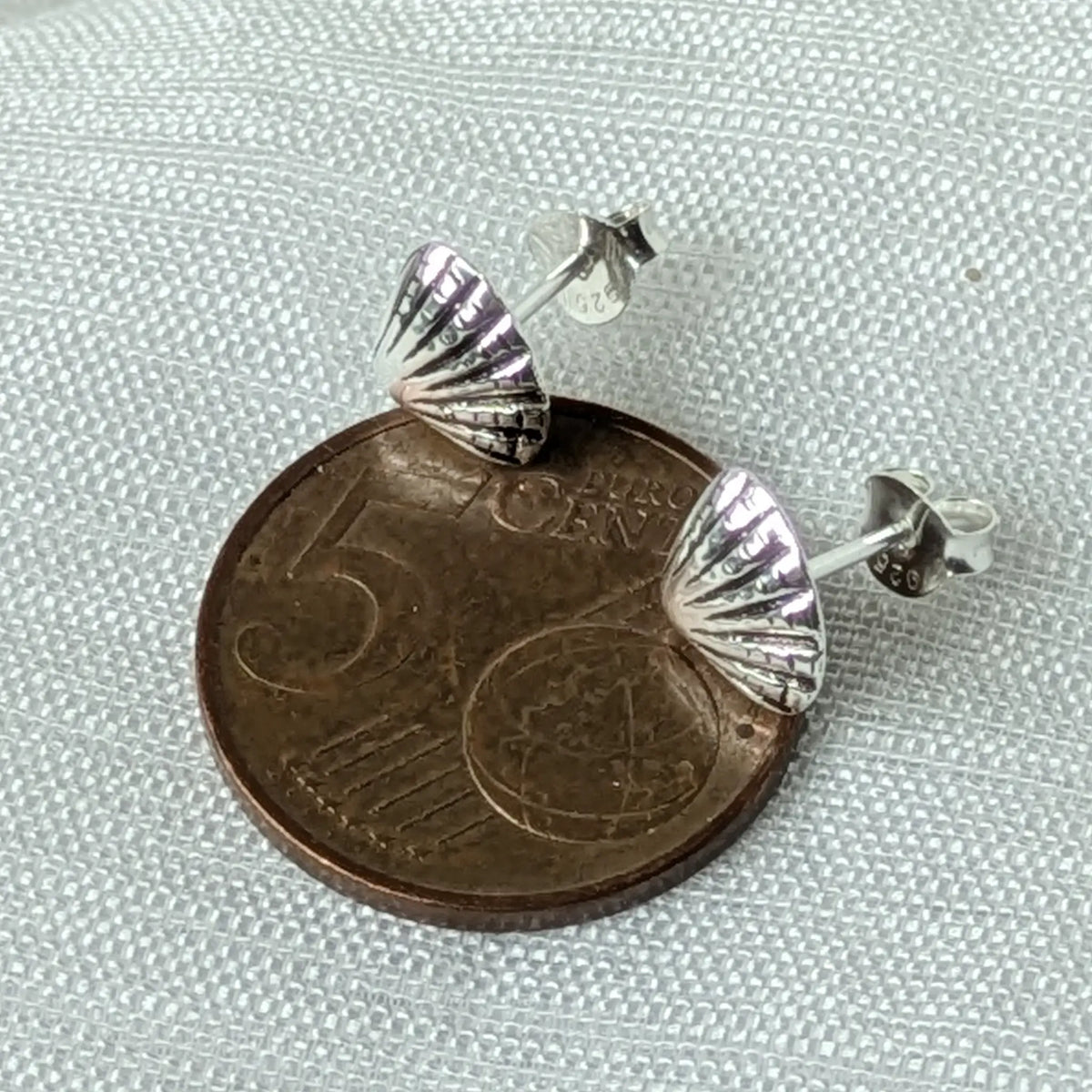 Größenvergleich der kleinen Muschel-Ohrringe, liegend auf einer 5-Cent-Münze, um die zierlichen Proportionen exakt zu zeigen.