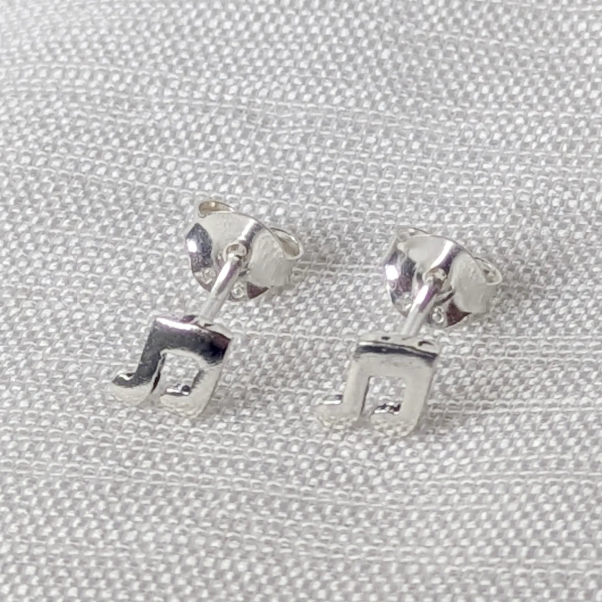 Paar Ohrstecker in Notenform aus 925 Silber, Frontansicht auf hellem Stoff