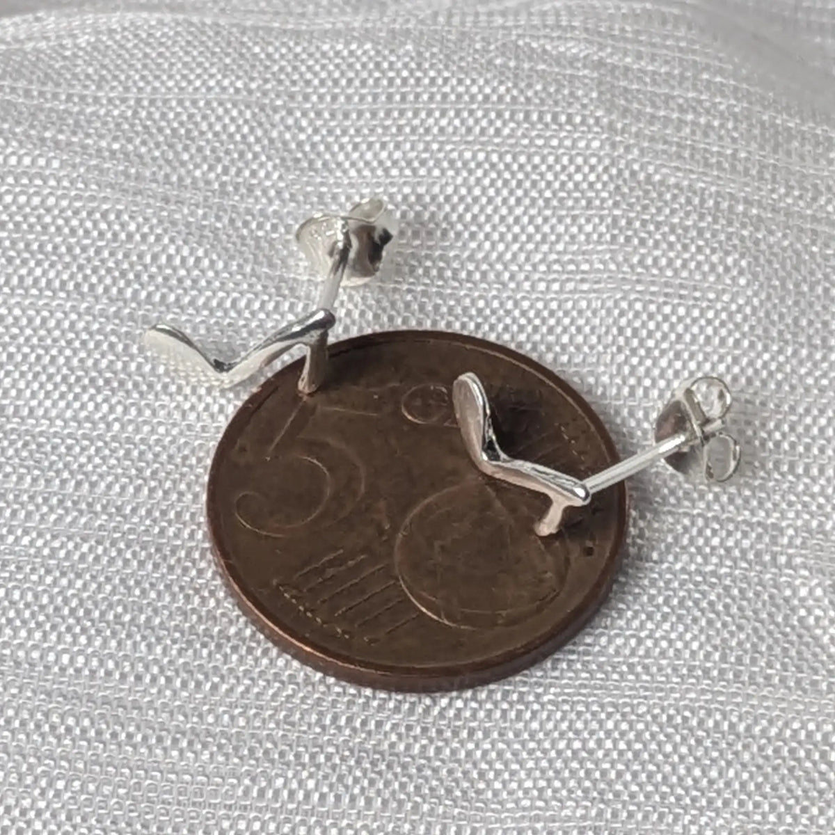 Kleine Musiknoten-Silberohrstecker direkt auf einer 5-Cent-Münze, um die zierliche Größe zu veranschaulichen. 