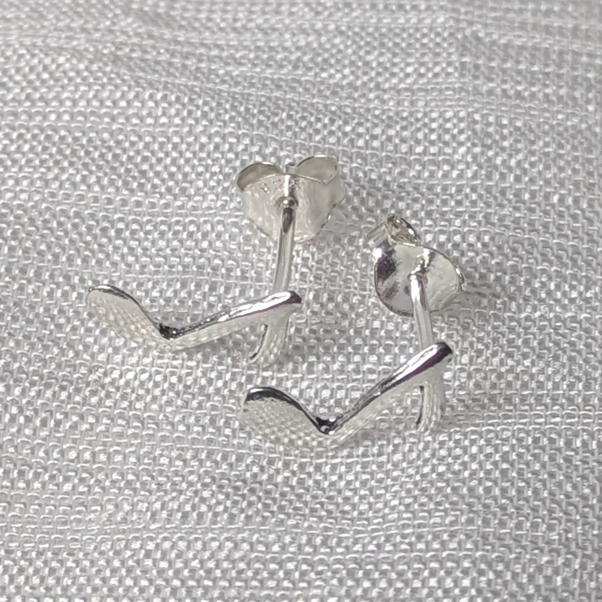 Frontalansicht der elegant geschwungenen Silberohrstecker im musikalischen Noten-Design.
