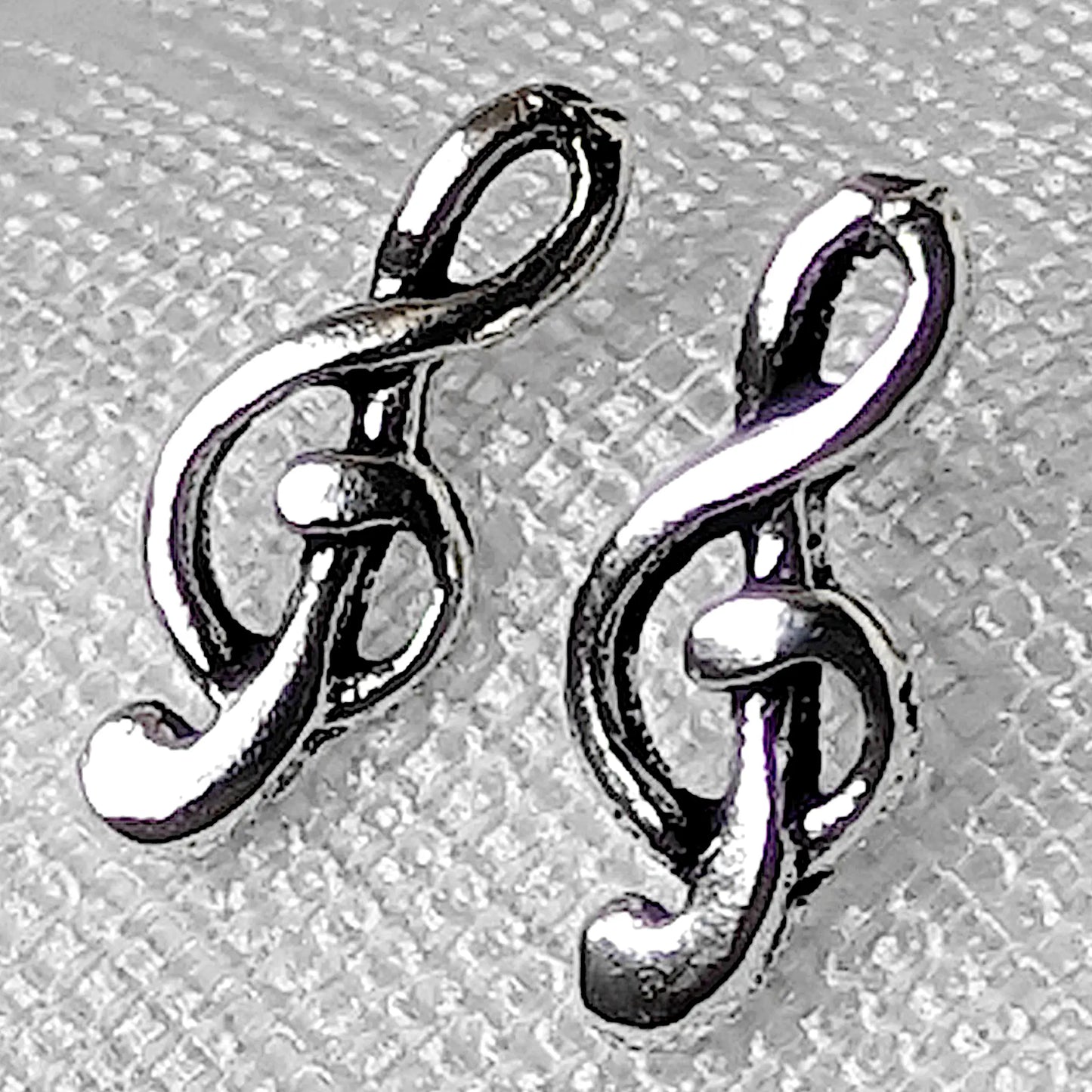 Nahaufnahme von zwei filigranen Notenschlüssel Ohrsteckern aus glänzendem 925 Sterling Silber